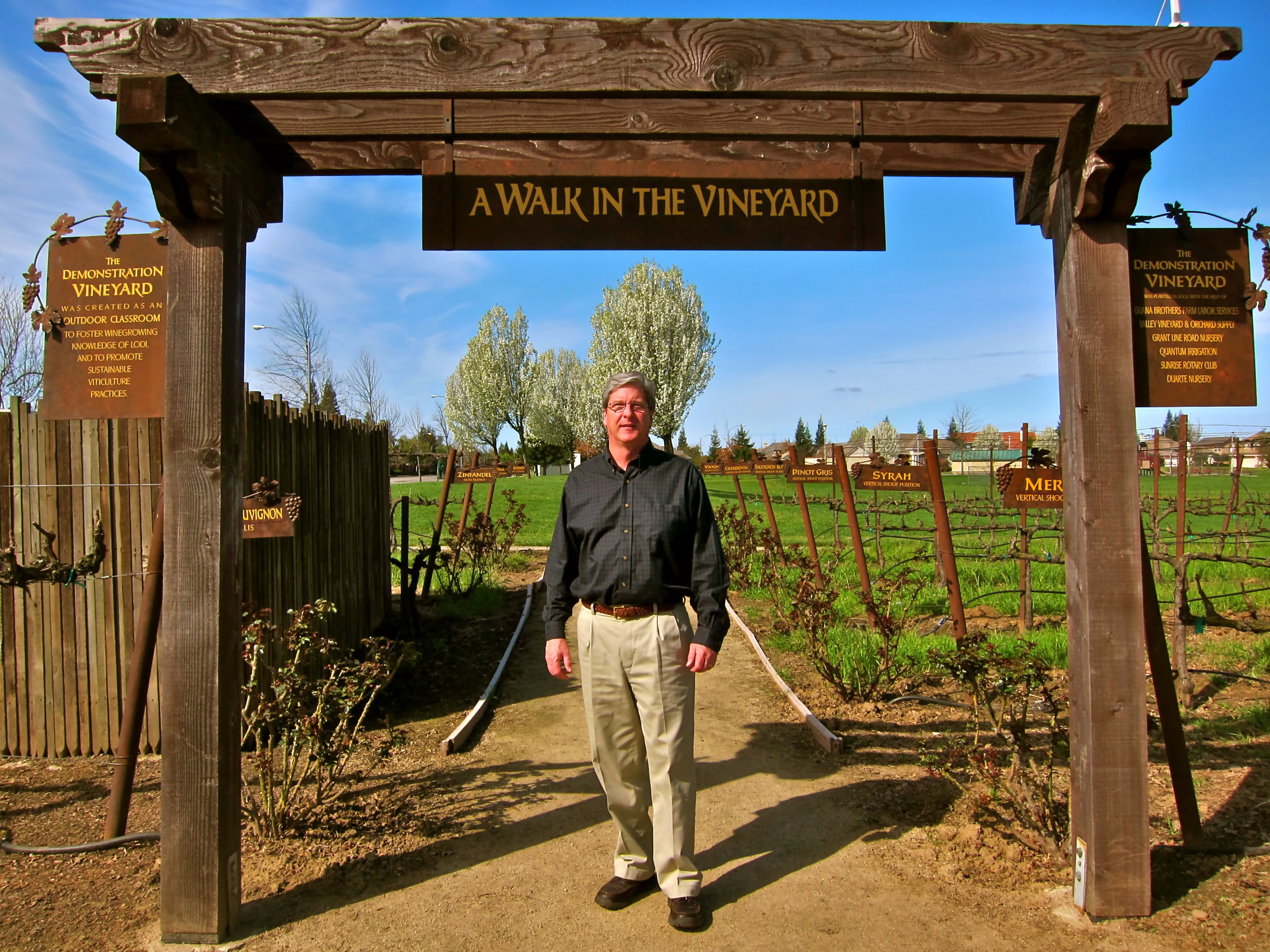 Man standing under vineyard entrance sign at Lodi Winegrape Commission.