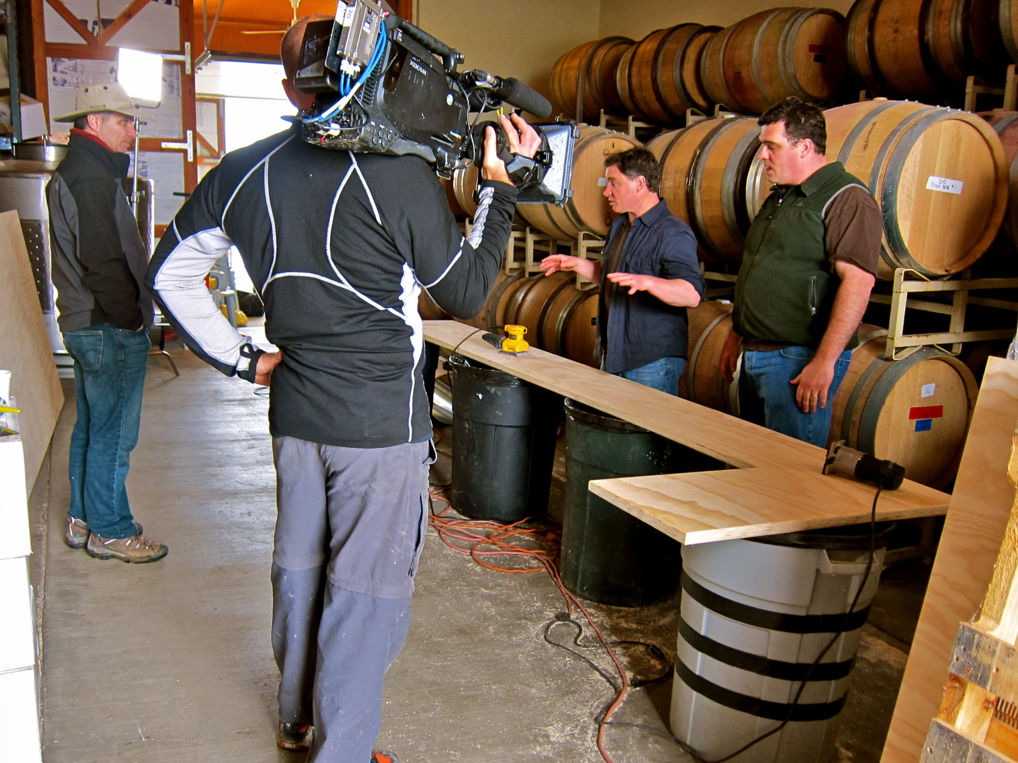 Filming a wine industry interview at a barrel room with wine barrels in the background.