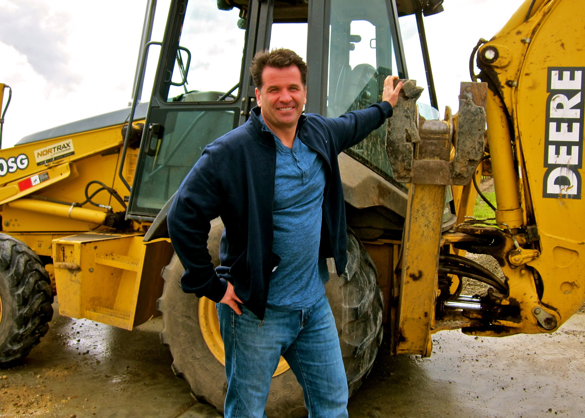 Man standing next to a yellow John Deere tractor at a vineyard in Lodi, California.