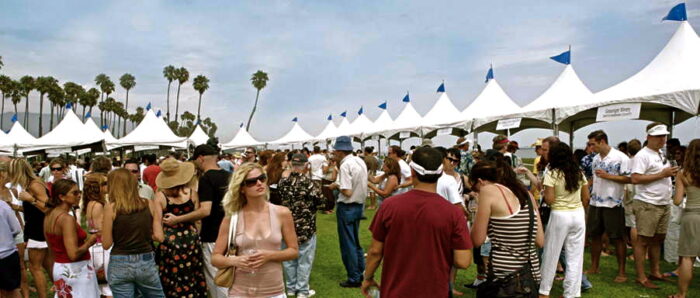 Crowd at Lodi Winegrape Commission outdoor event with tents and palm trees in the background.