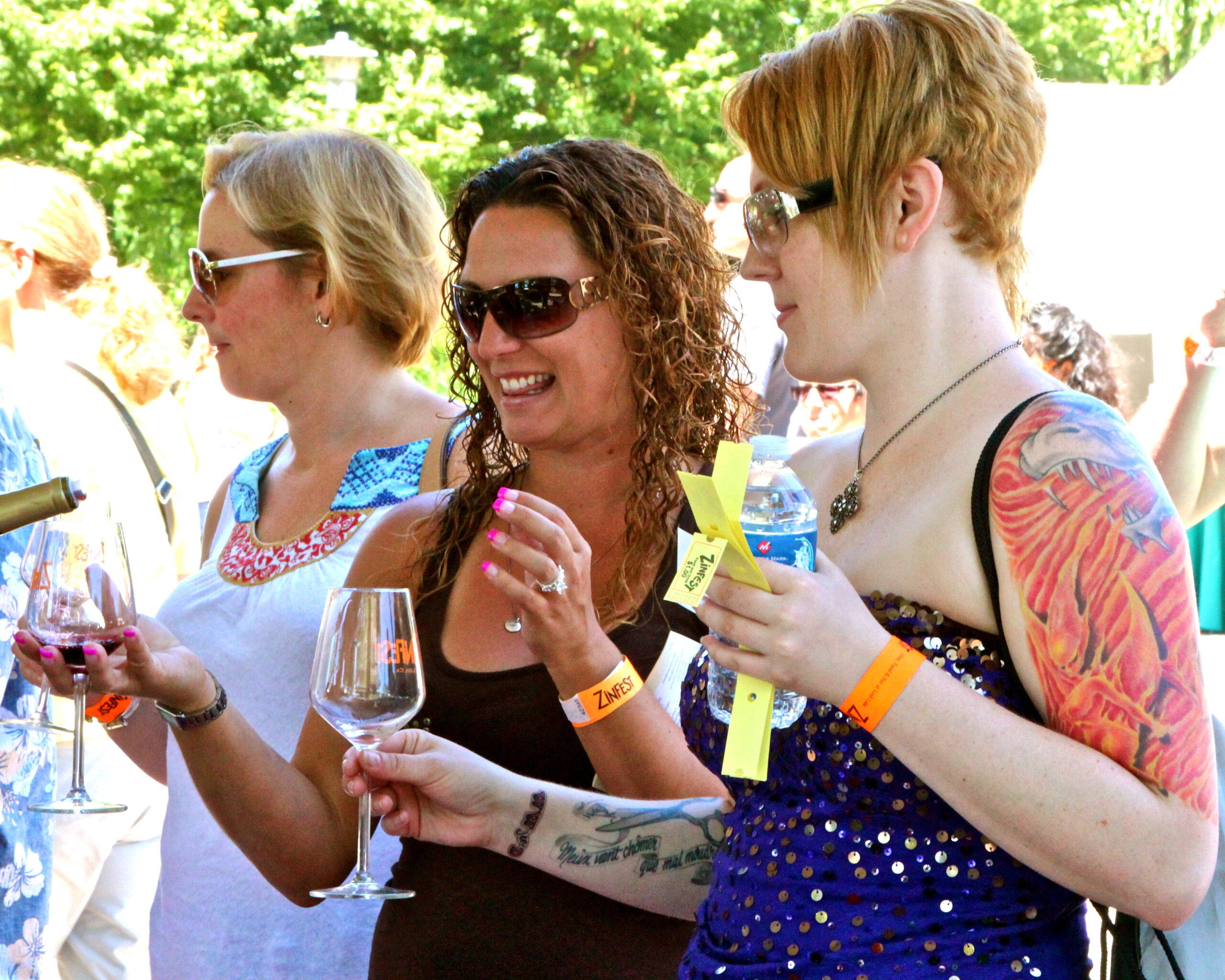 Women enjoying wine tasting at Lodi Winegrape Commission event outdoors.