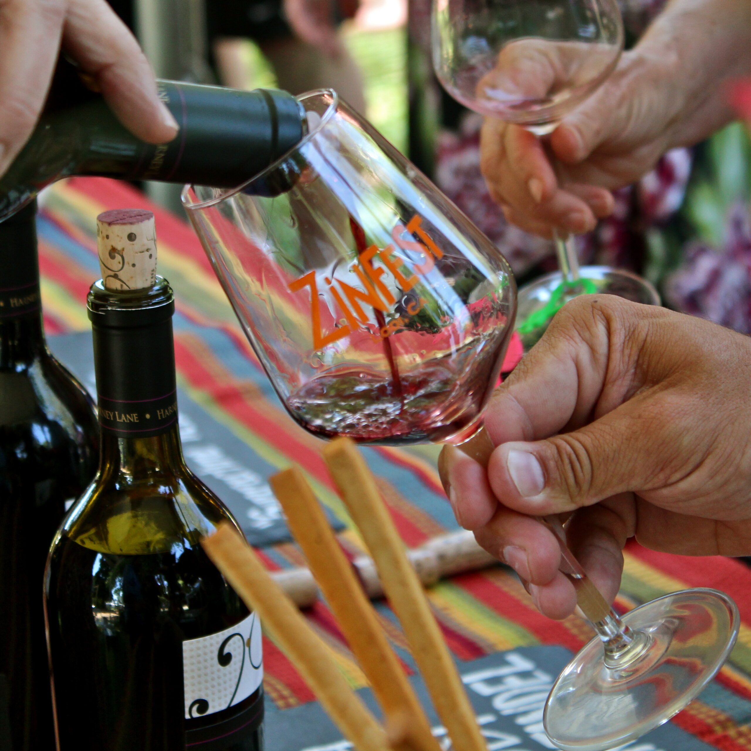 People enjoying wine tasting at Lodi Winegrape Commission event with wine glasses and bottles.