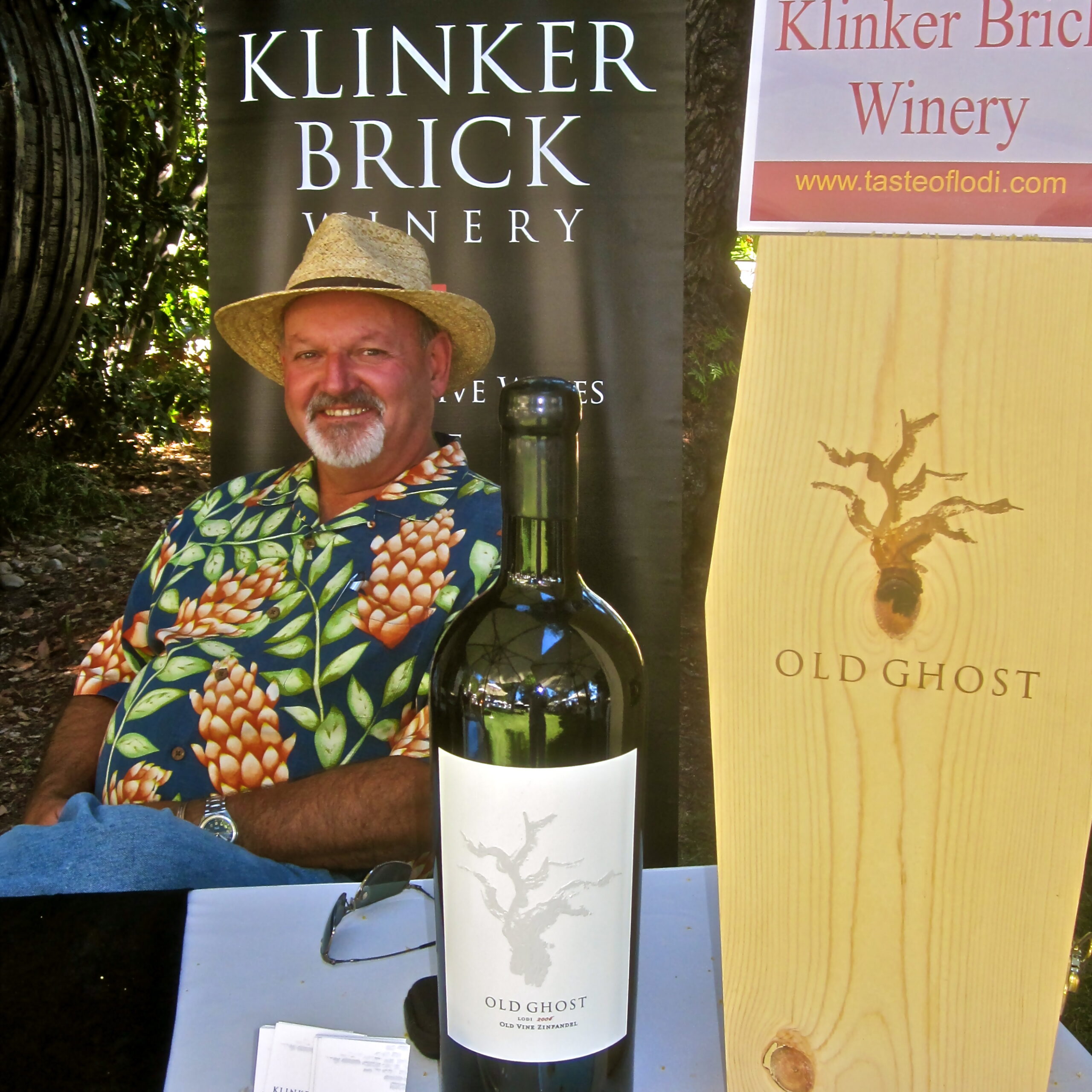 Man at Klinker Brick Winery with Old Ghost wine bottle and banners in the background.