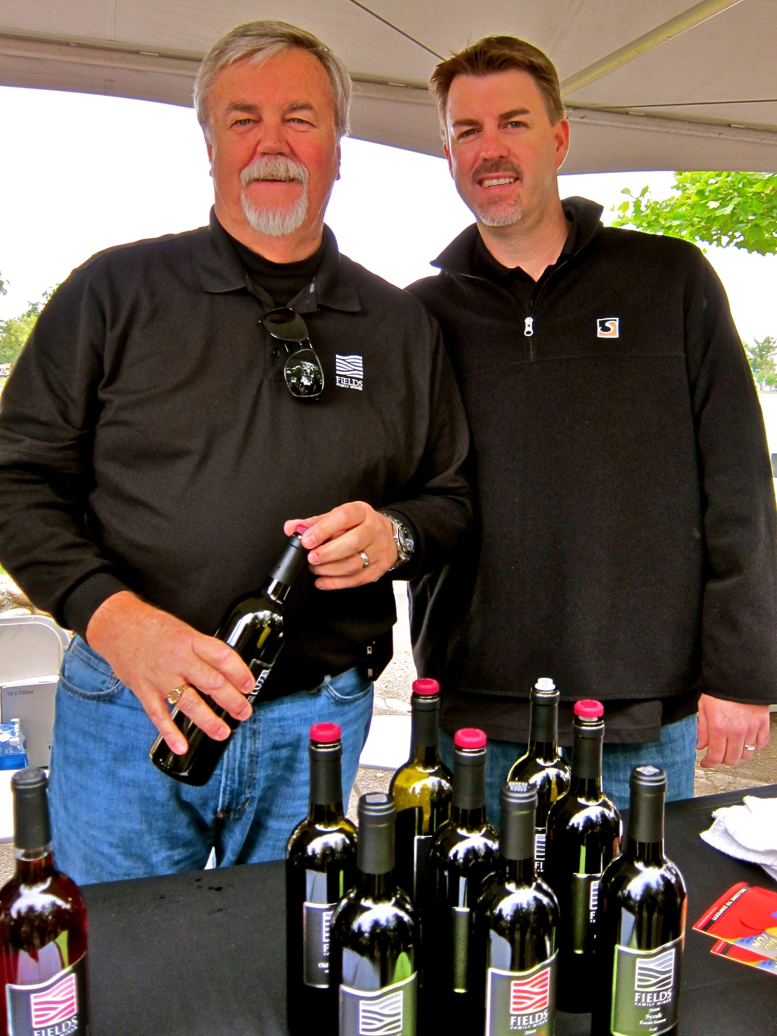 Two men at a wine tasting event with bottles of wine on display, representing Lodi Winegrape Commission.