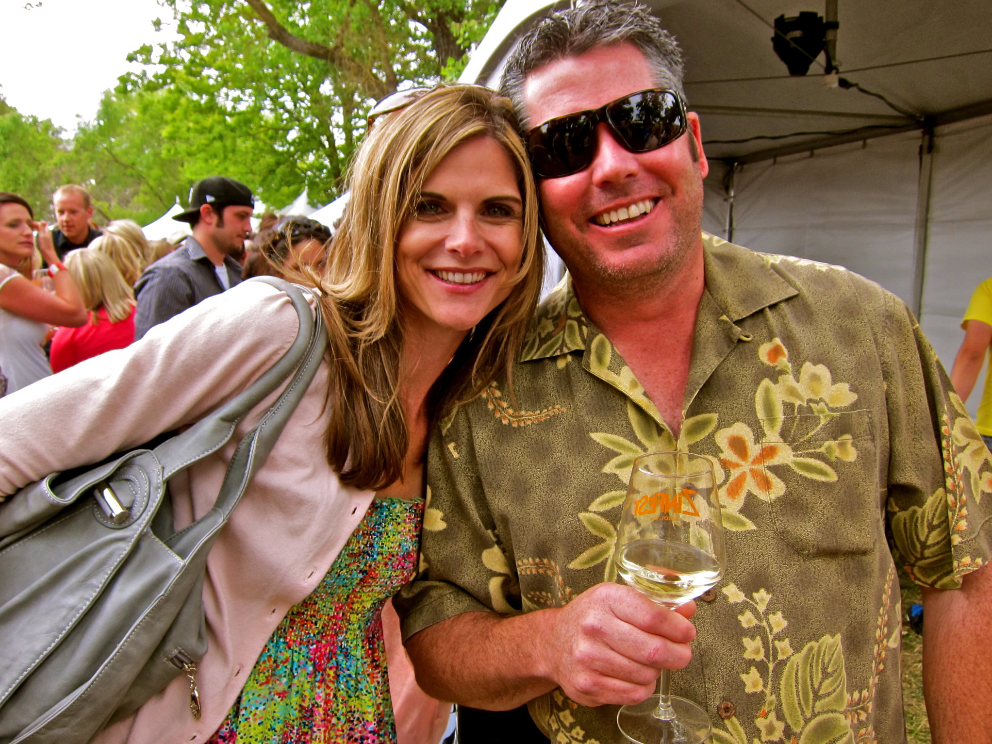 Smiling man and woman at Lodi Winegrape Commission event with wine glass and outdoor setting.