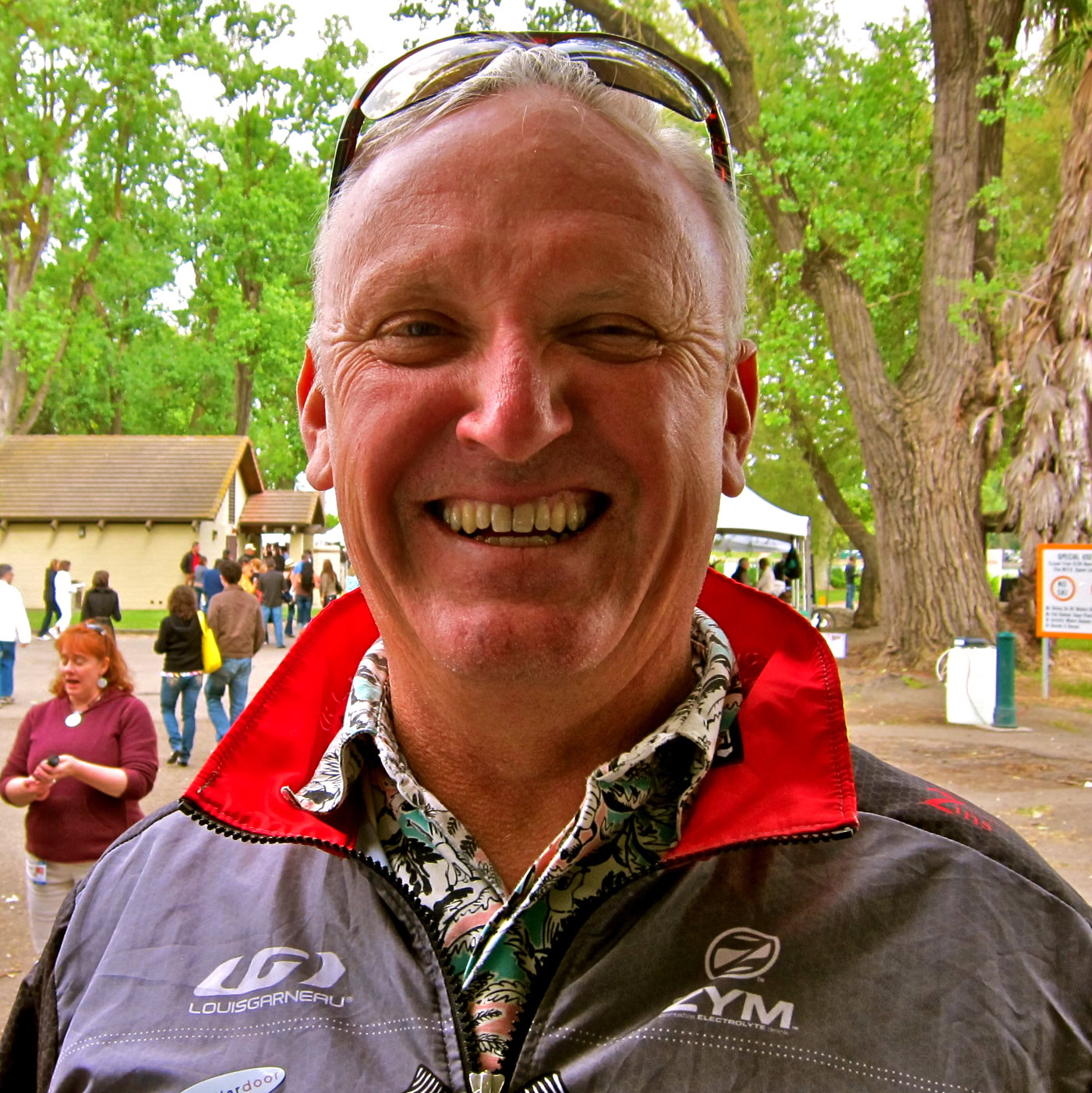 Smiling man at Lodi Winegrape Commission event with trees and people in background.
