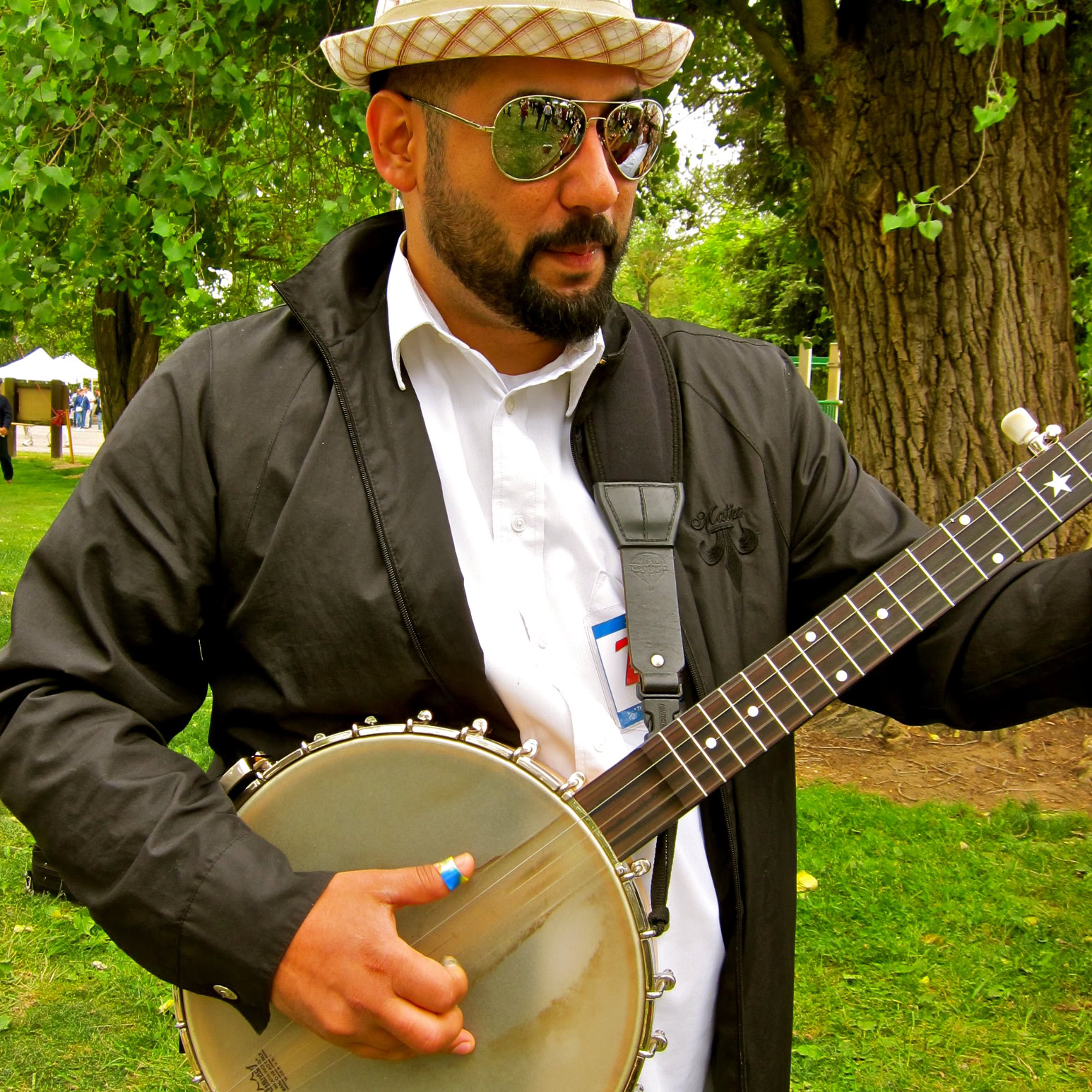 Man playing banjo outdoors at Lodi Winegrape Commission event with trees in background.
