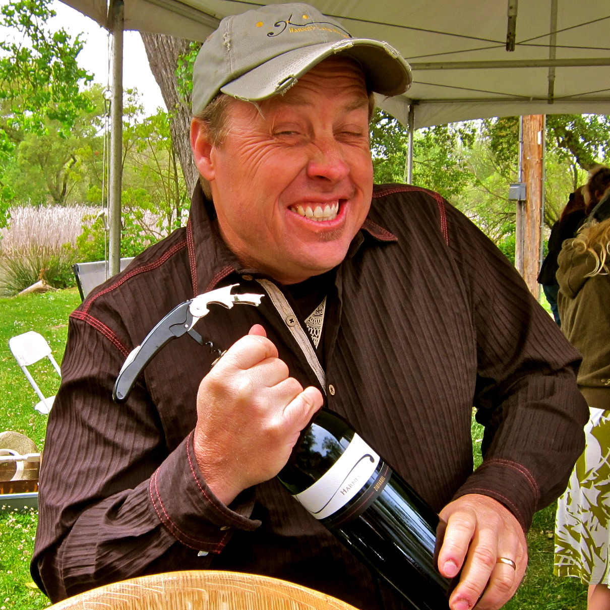 Happy man holding a wine bottle at a Lodi wine event outdoors.