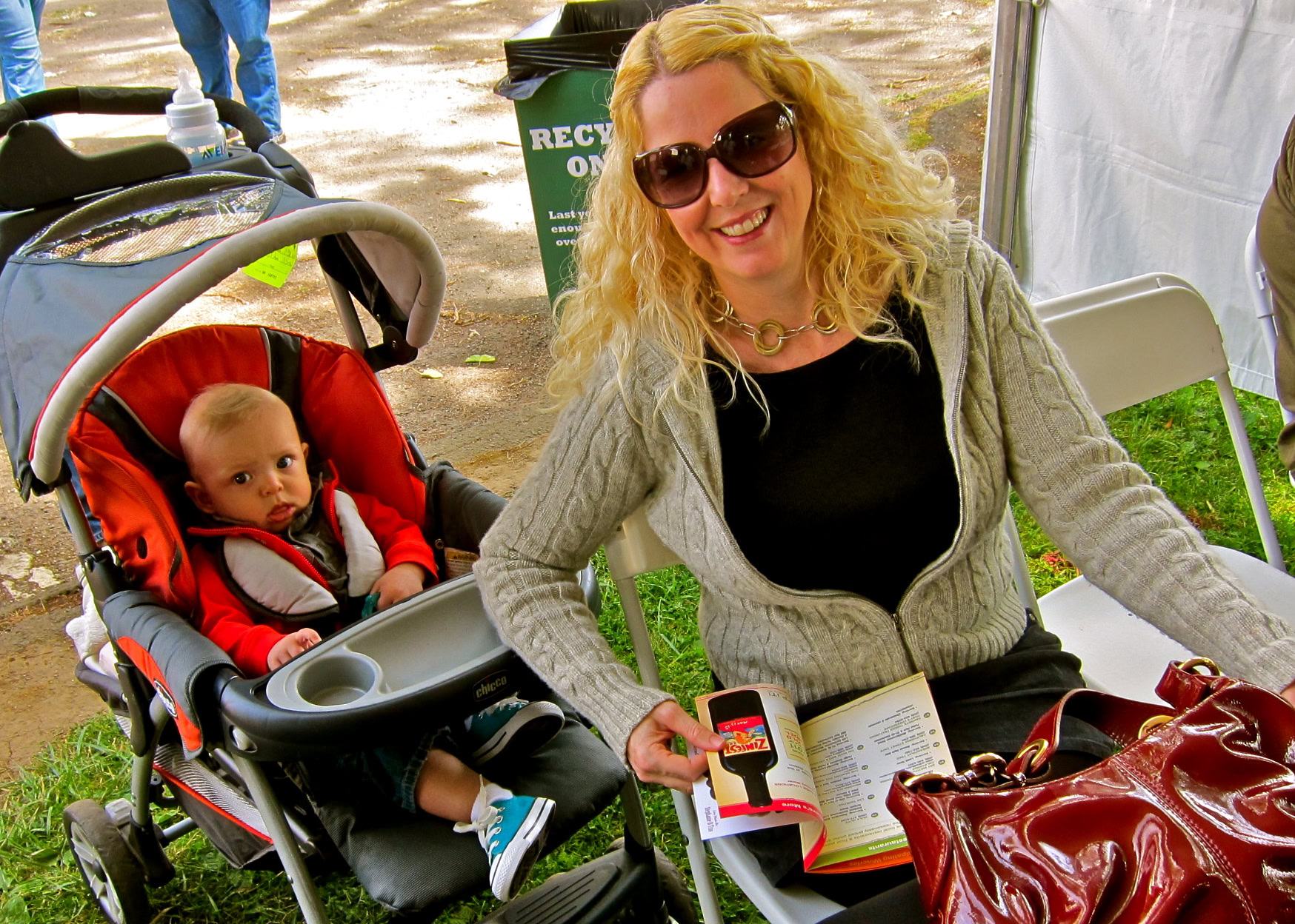 Woman smiling at a table with a baby in a stroller at a Lodi wine event.