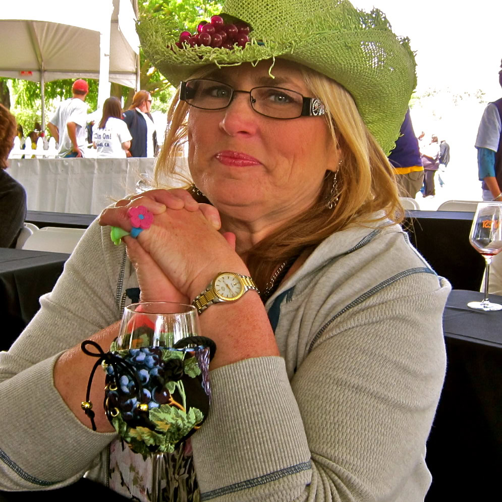 Woman wearing a green hat with grapes at Lodi Winegrape Commission event.