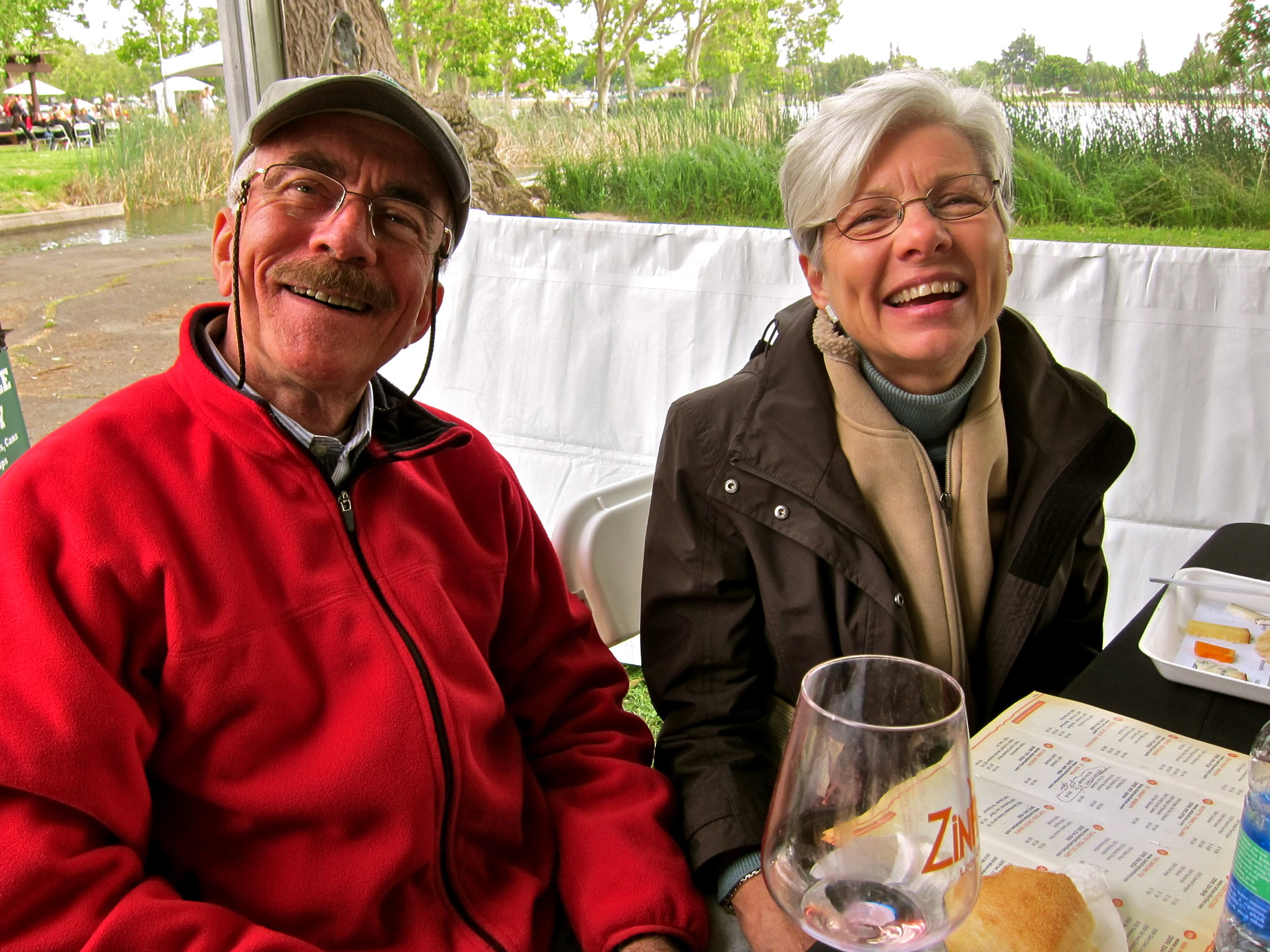 Smiling seniors enjoying wine tasting outdoors at a Lodi Winegrape Commission event.