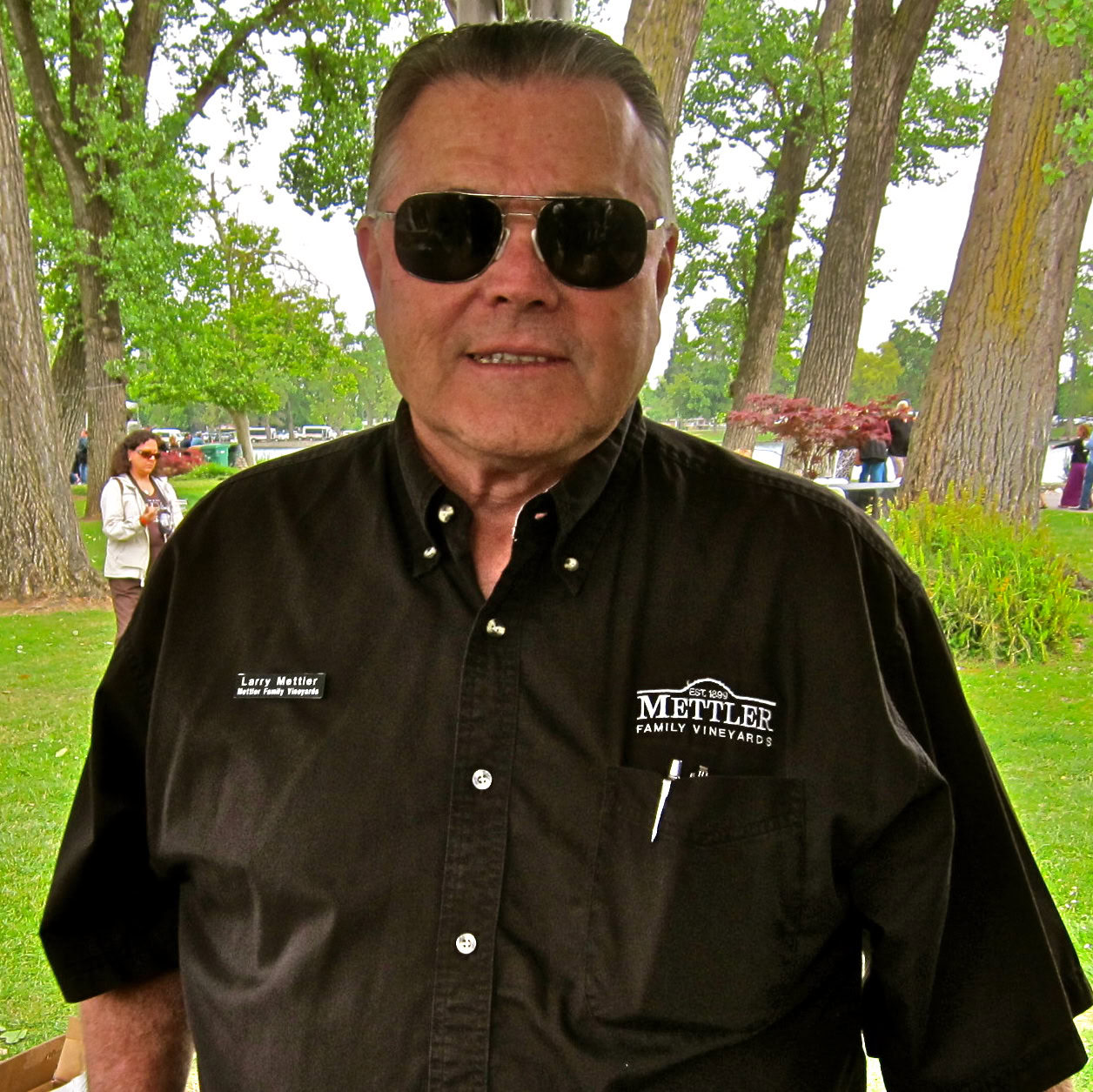 Man in black shirt with sunglasses at Lodi Winegrape Commission event outdoors.