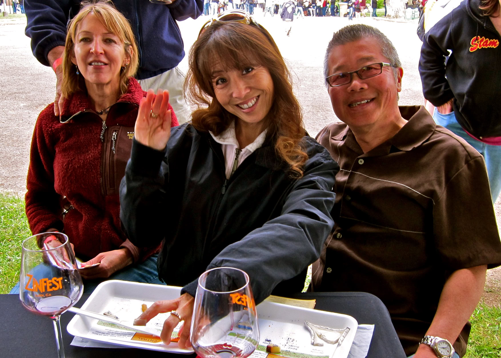Smiling people at Lodi Winegrape Commission event enjoying wine tasting outdoors.
