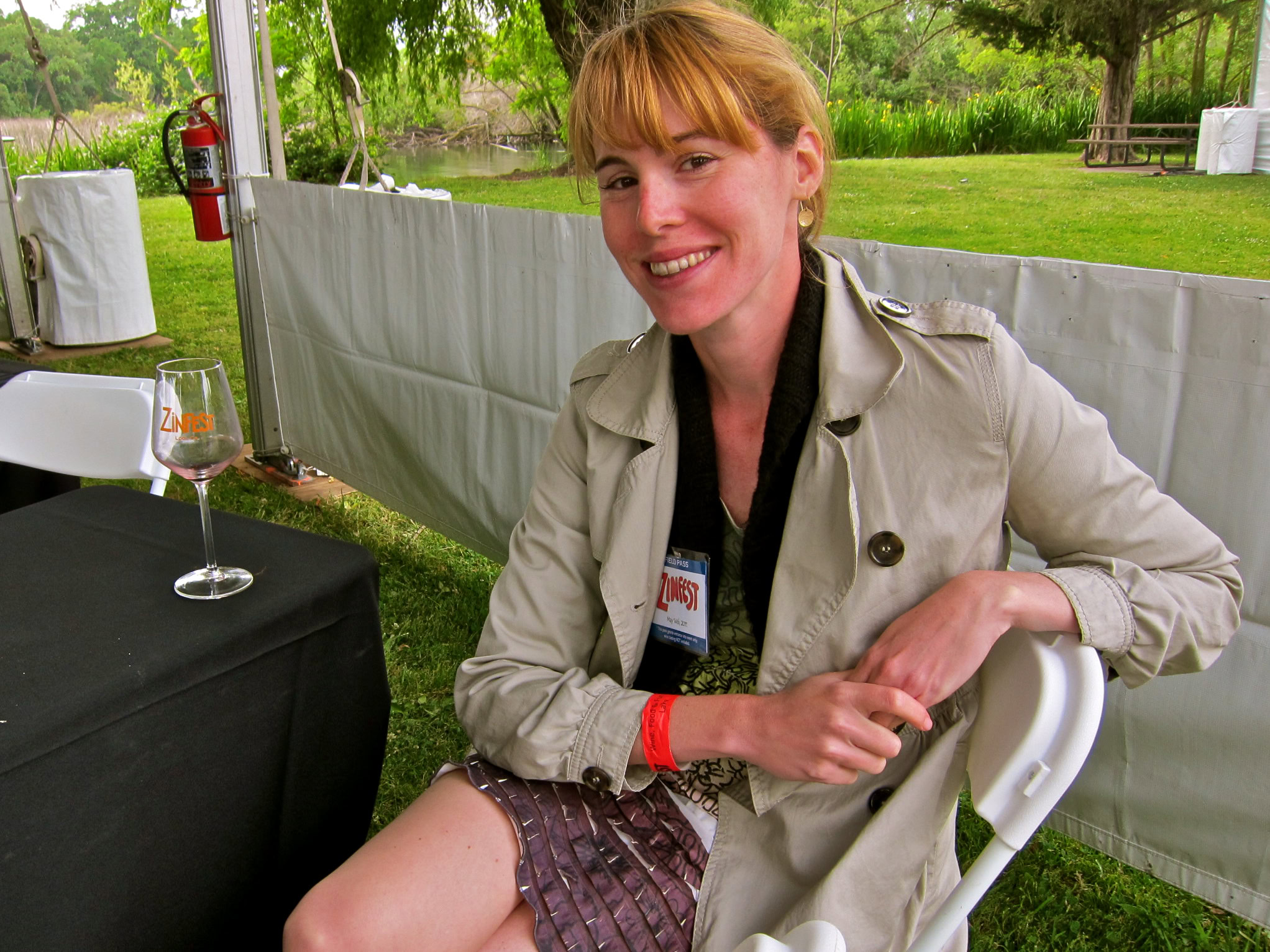 Smiling woman at Lodi Winegrape Commission event outdoors with wine glass and badge.