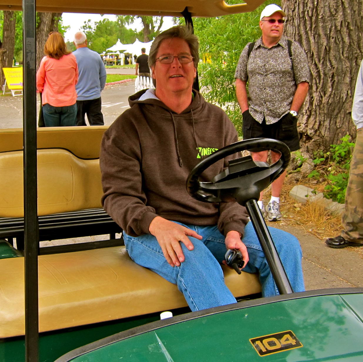 Man sitting in a golf cart at a Lodi wine event with people in the background.