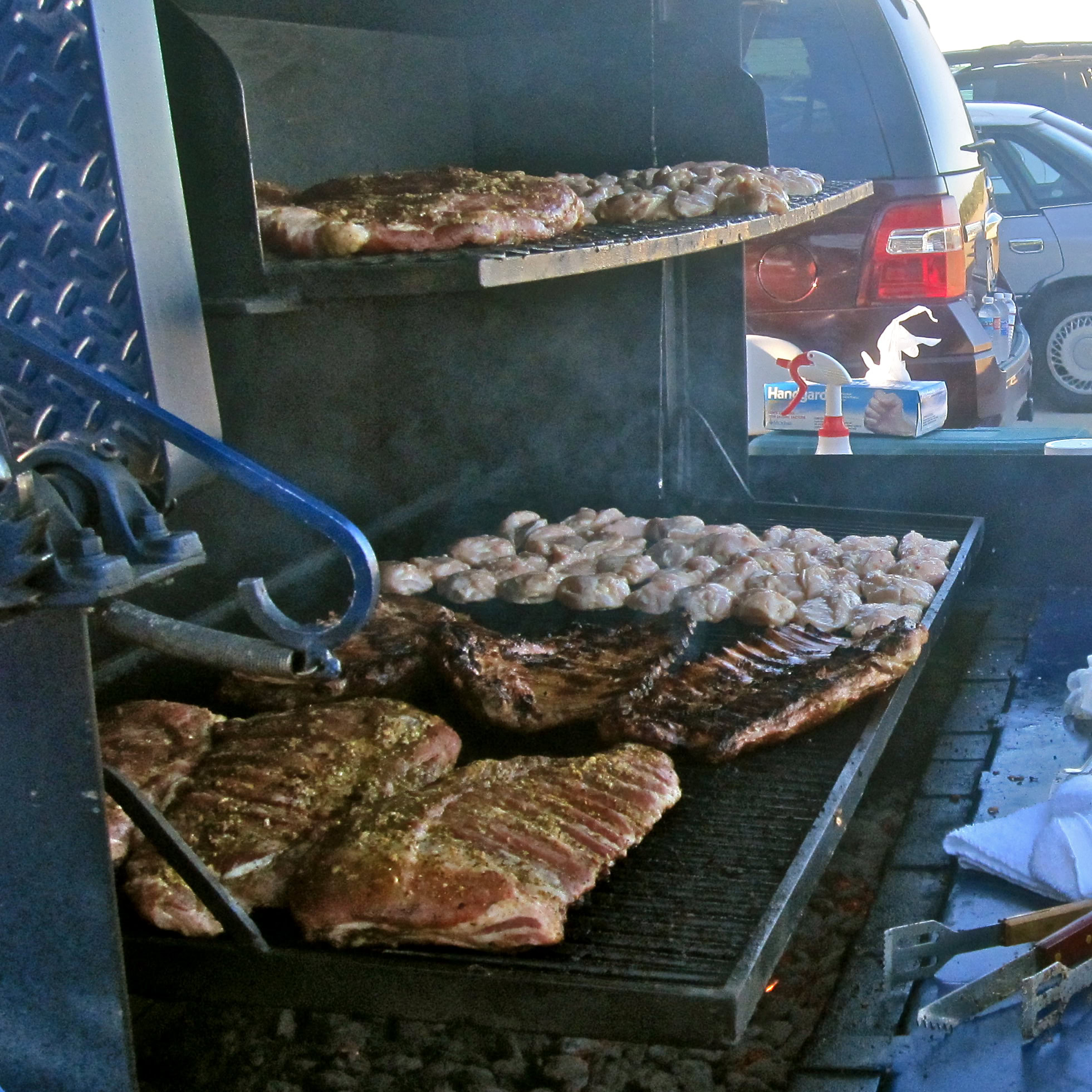 Barbecue grill with various meats cooking, including steaks and chicken, at Lodi Winegrape Commission event.