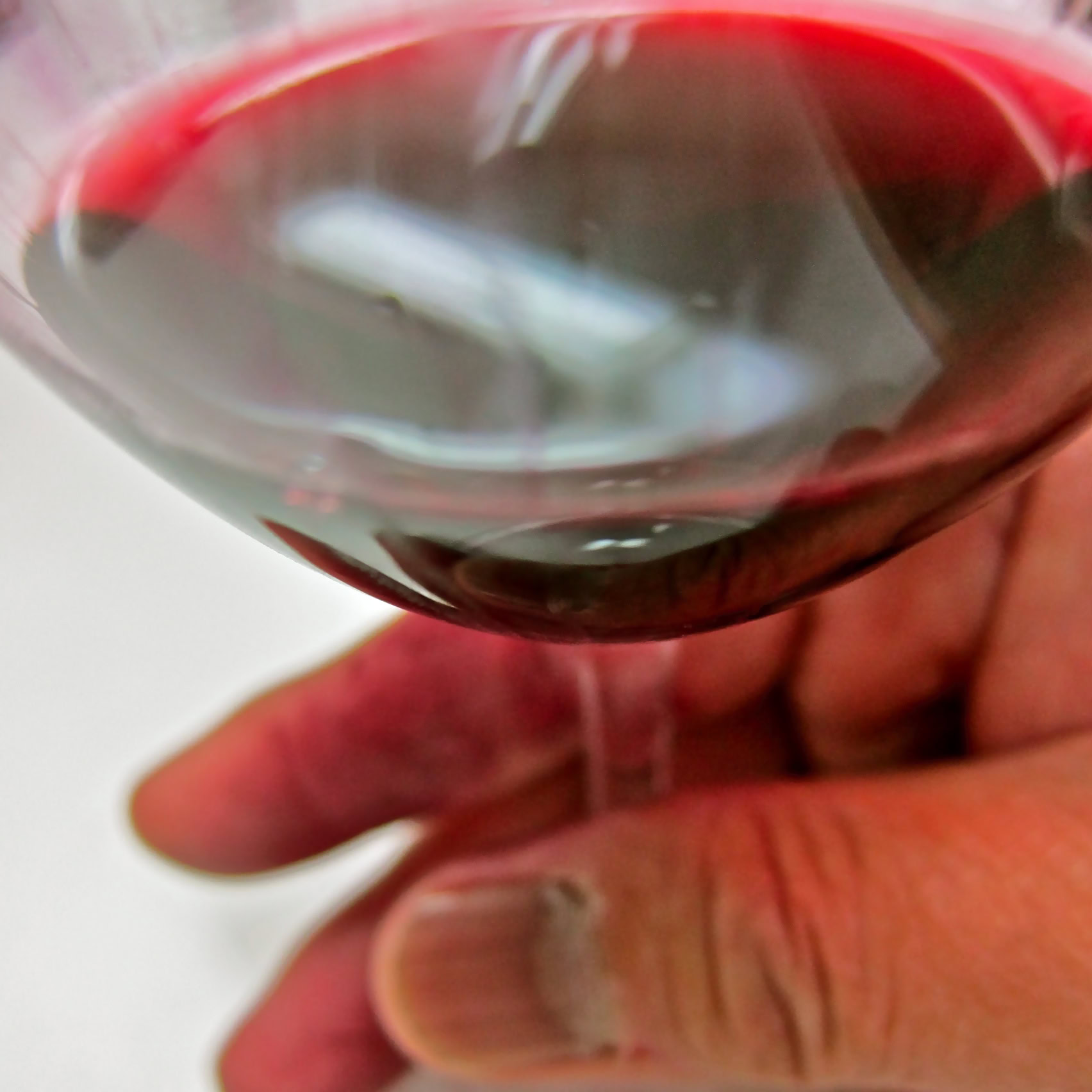Close-up of a hand holding a glass of red wine from Lodi Winegrape Commission.