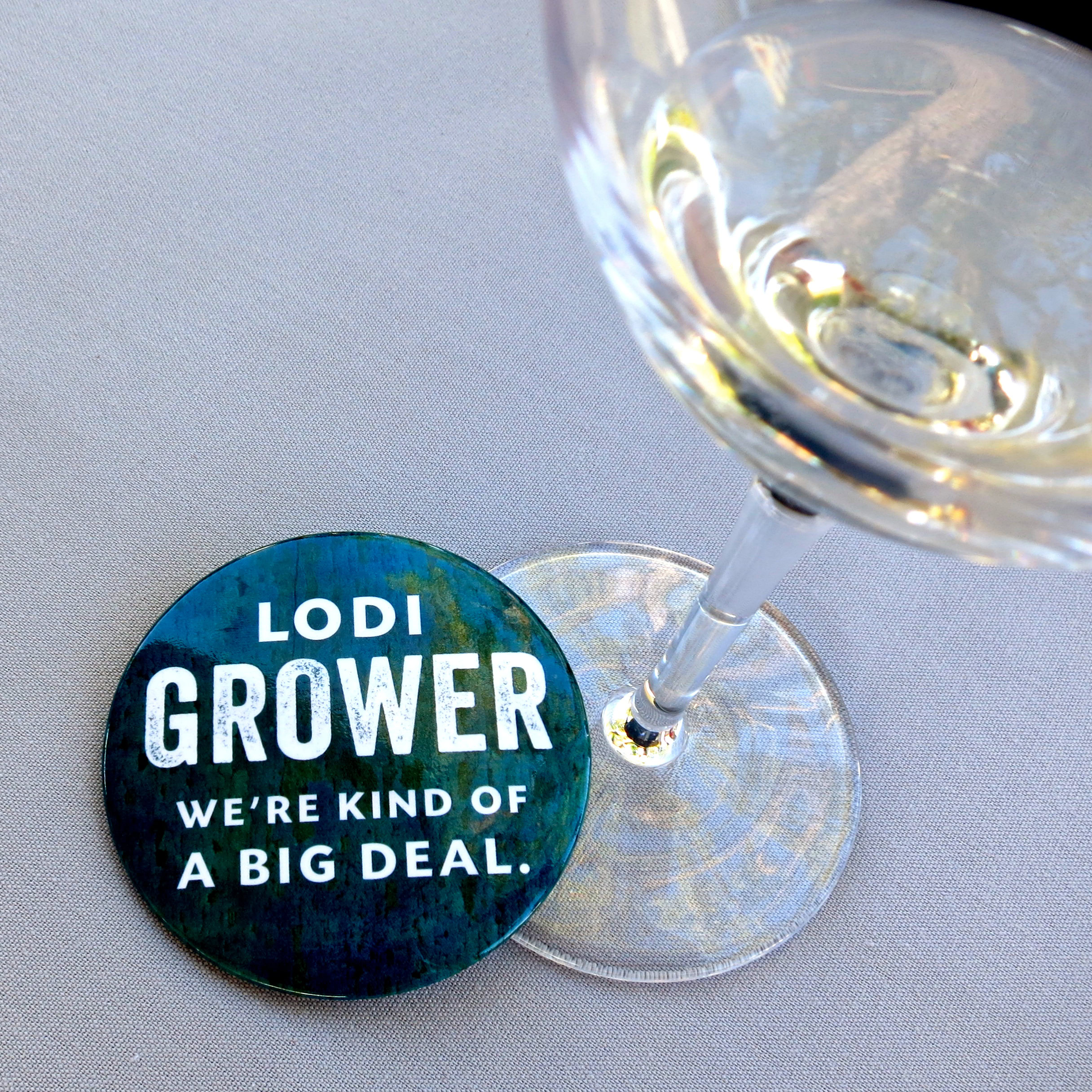 Close-up of a wine glass and a badge with Lodi Grower text for wine industry promotion.