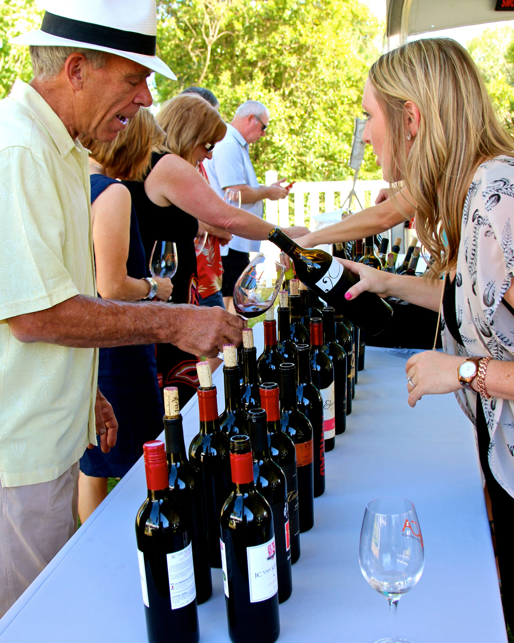 People tasting wine at a Lodi Winegrape Commission event with bottles on display.