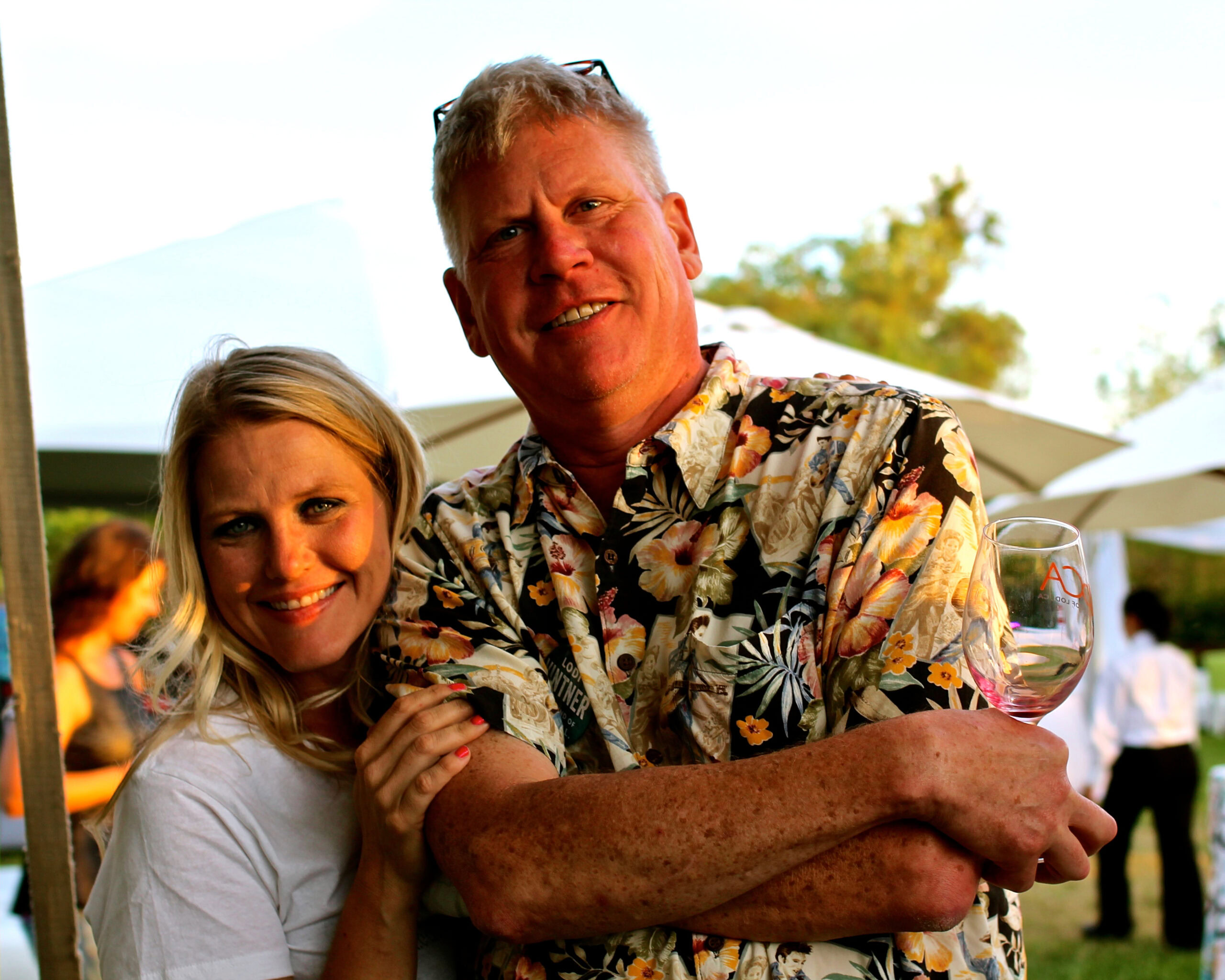 Smiling man and woman at Lodi Winegrape Commission outdoor event with wine glass.