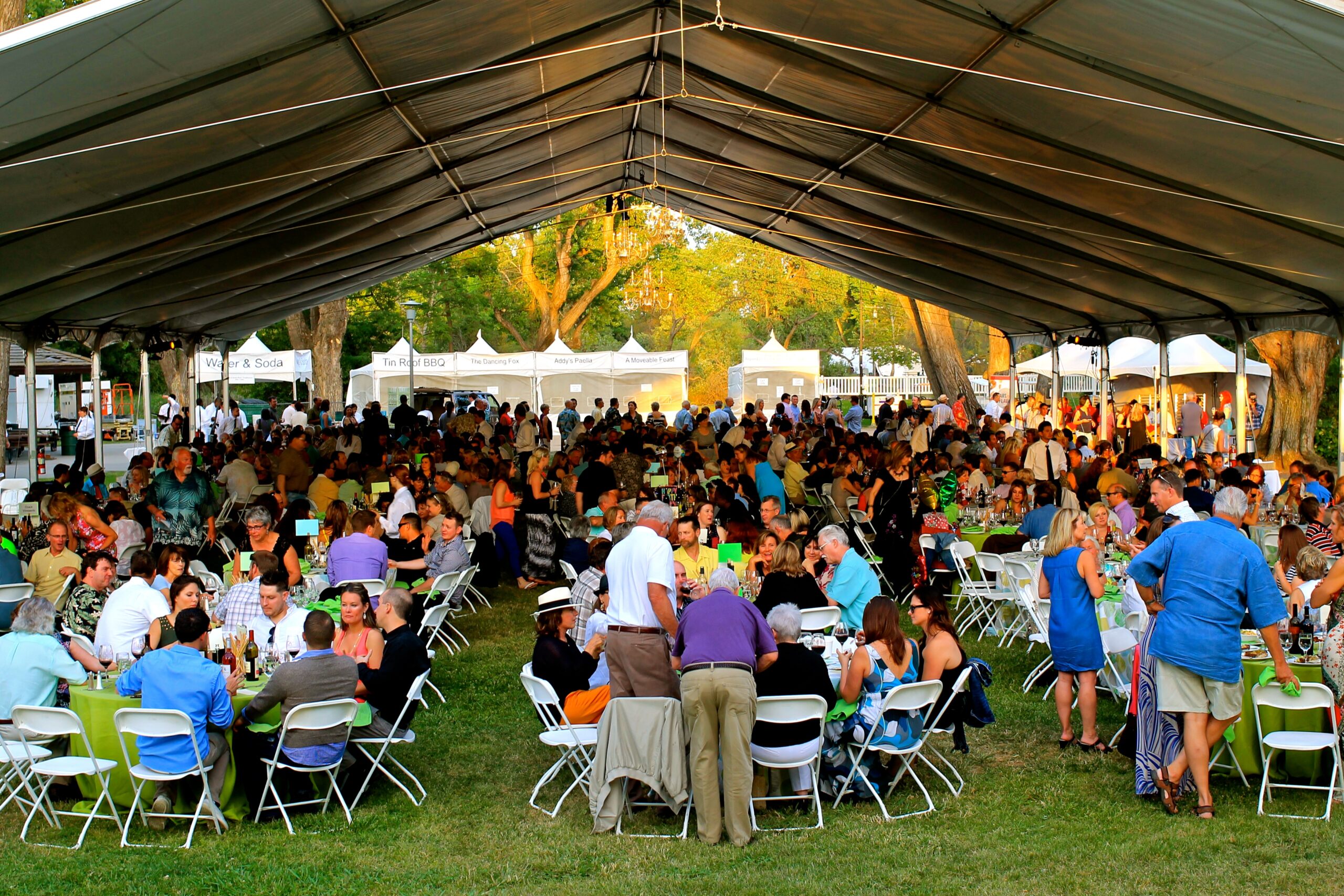Large outdoor event under a tent with many people enjoying wine tasting and socializing in Lodi, California.