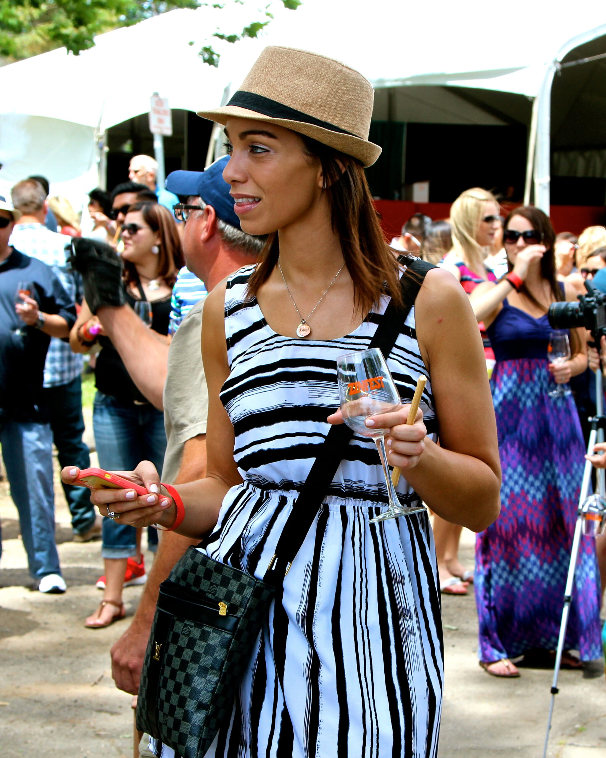Young woman at Lodi Winegrape Commission event holding a glass of wine and a smartphone.