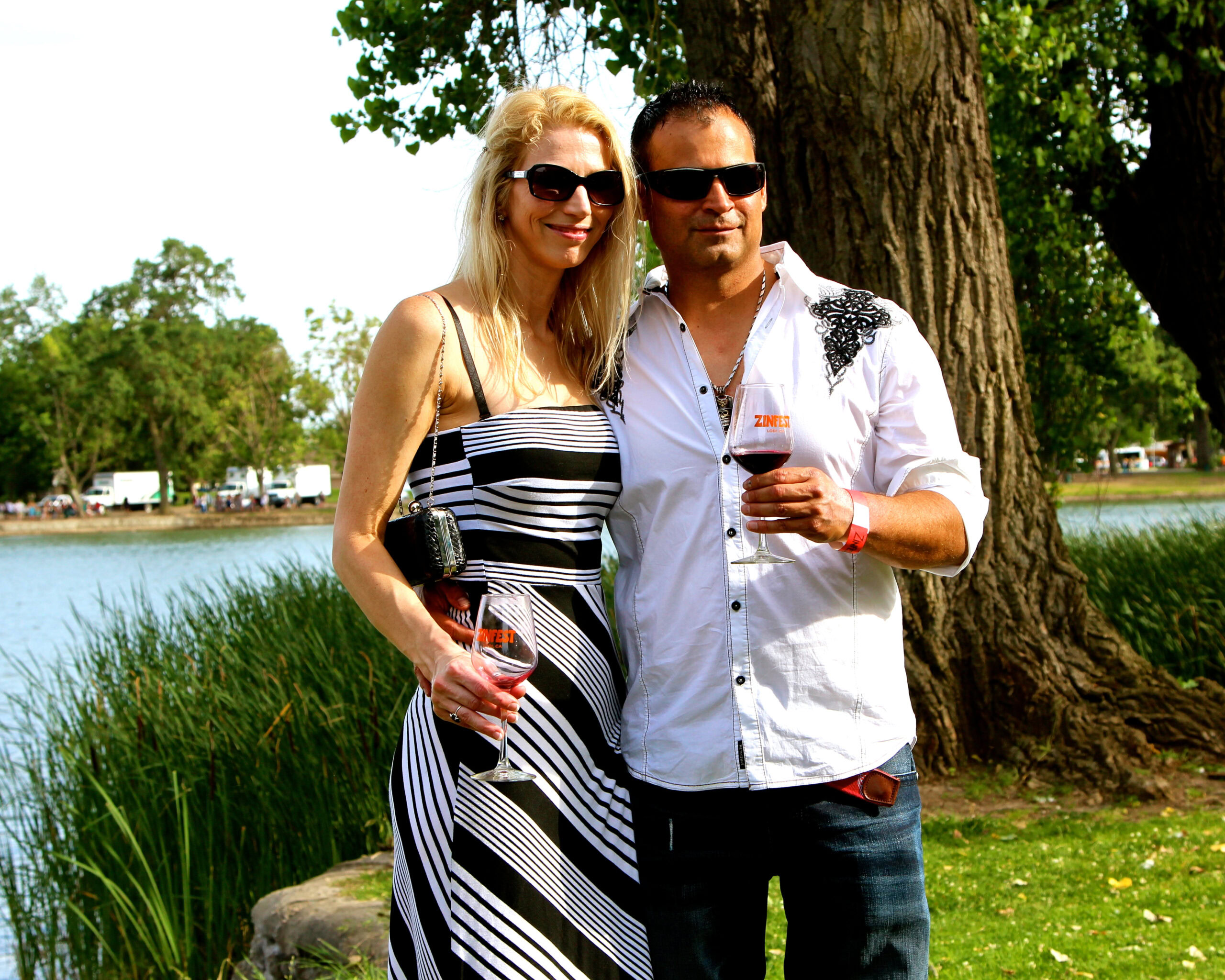 Couple enjoying wine outdoors near a lake with trees and grass in Lodi, California.