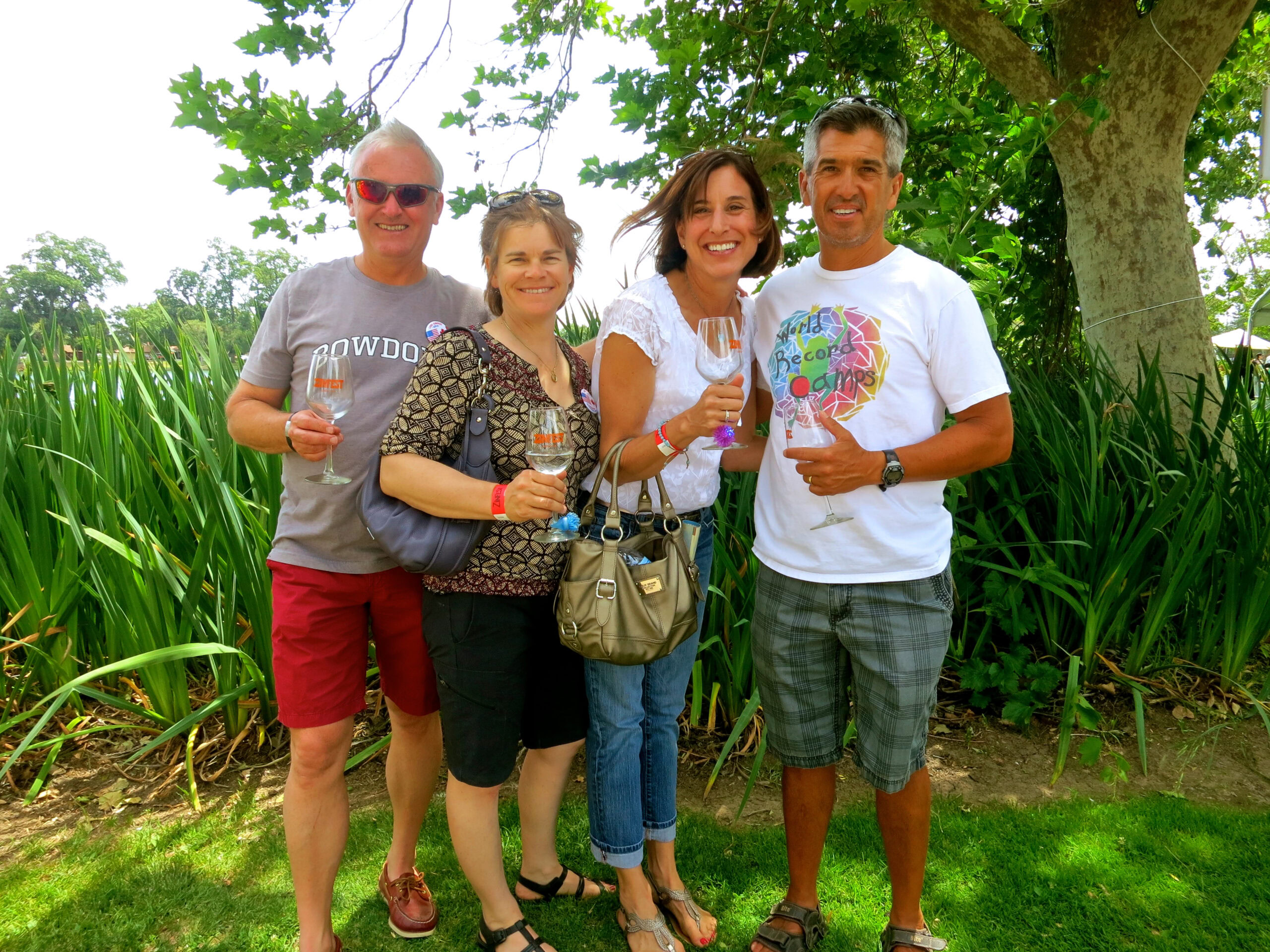 Group of four people enjoying wine tasting outdoors at Lodi Winegrape Commission event.