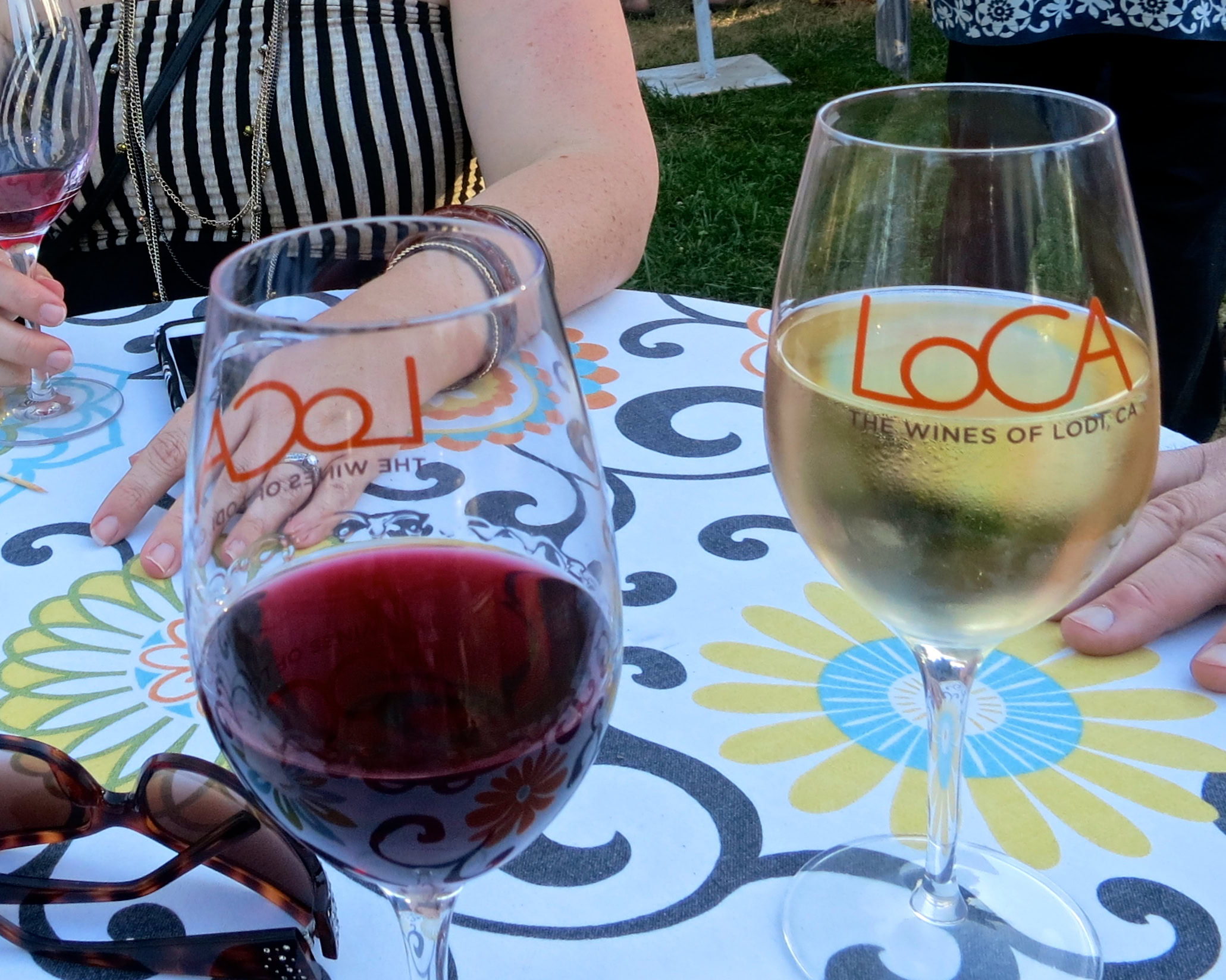 Two wine glasses, one with red wine and one with white wine, on a table with a floral tablecloth at Lodi Winegrape Commission.