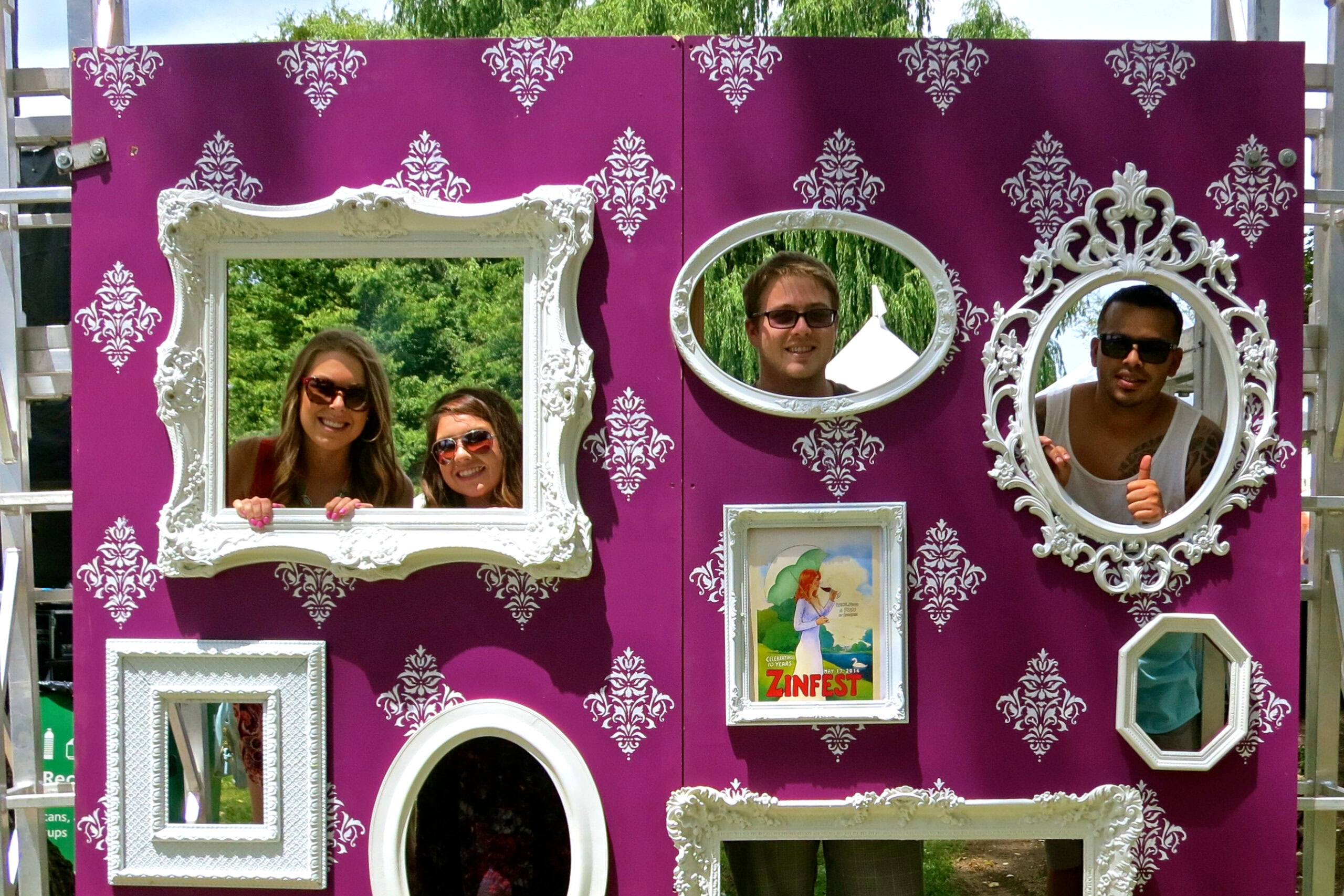 People enjoying a photo booth with ornate frames at a Lodi wine event.