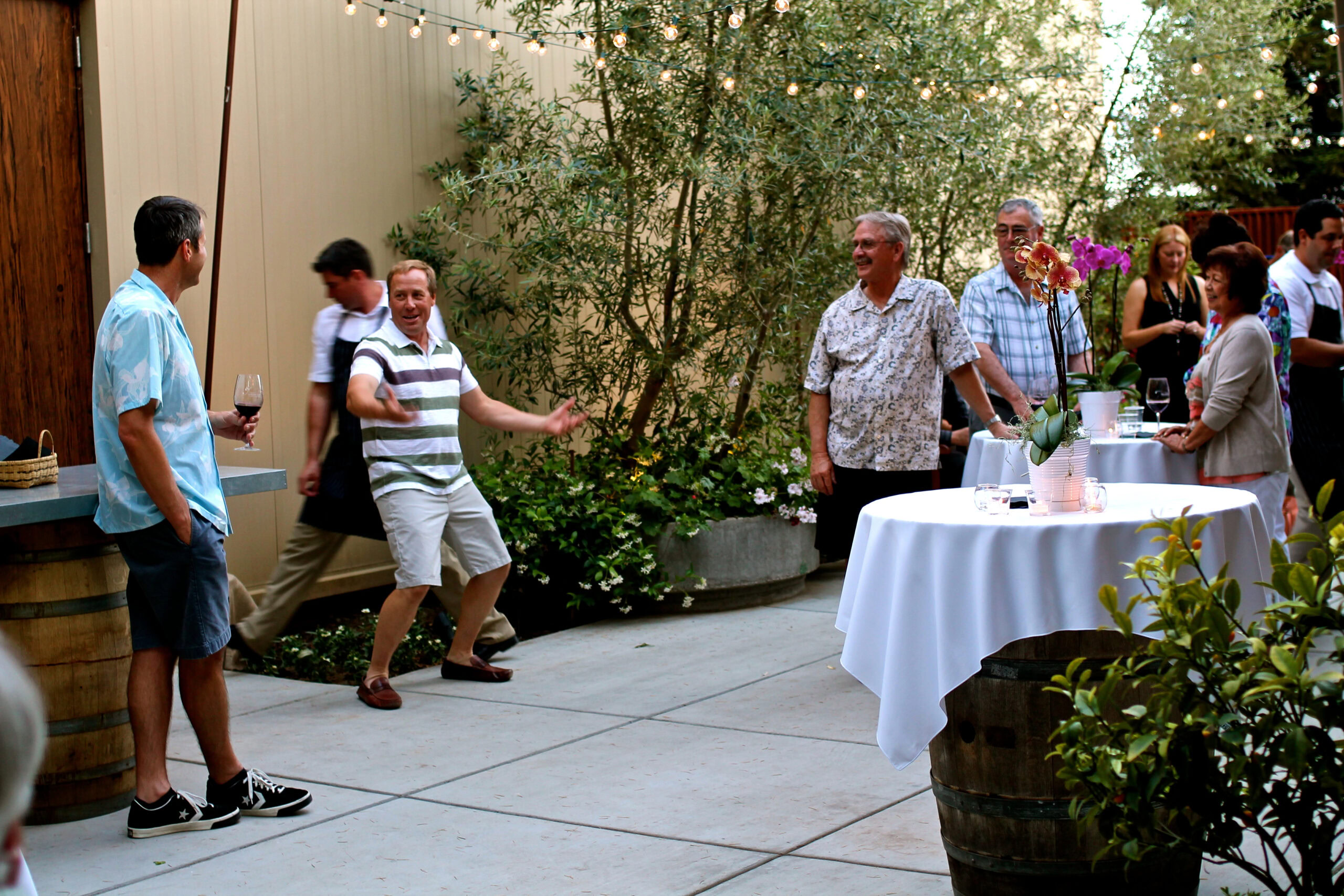 People enjoying a wine tasting event outdoors with tables, wine glasses, and lush greenery in Lodi, California.