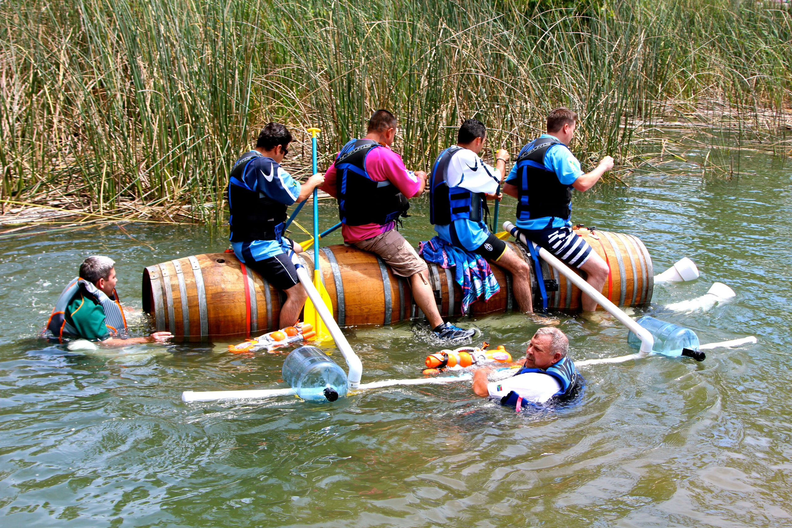 Group of people on a makeshift raft in water, participating in an outdoor activity.