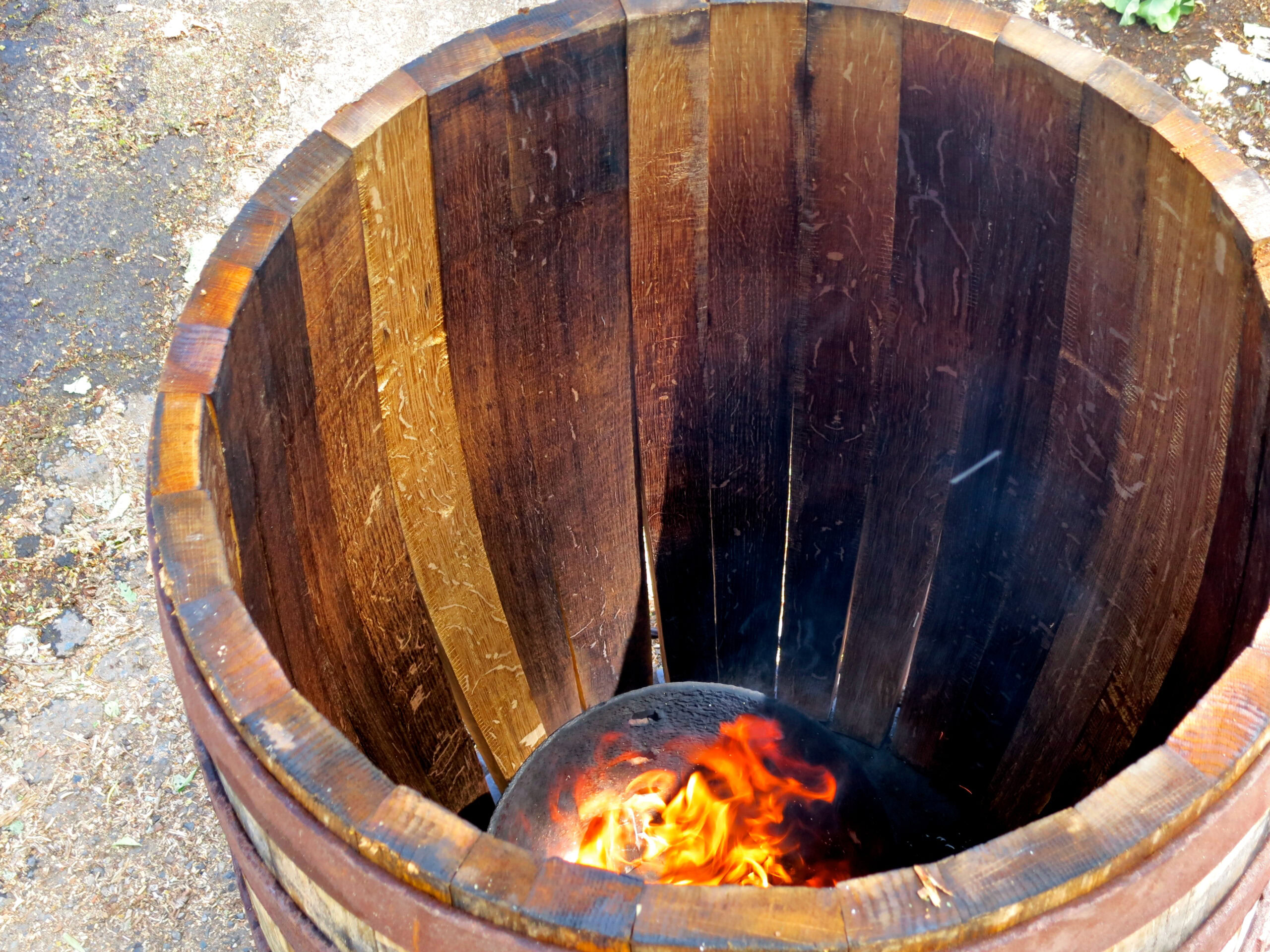 Wooden wine barrel with a small fire inside, used for wine aging and fermentation in Lodi, California.