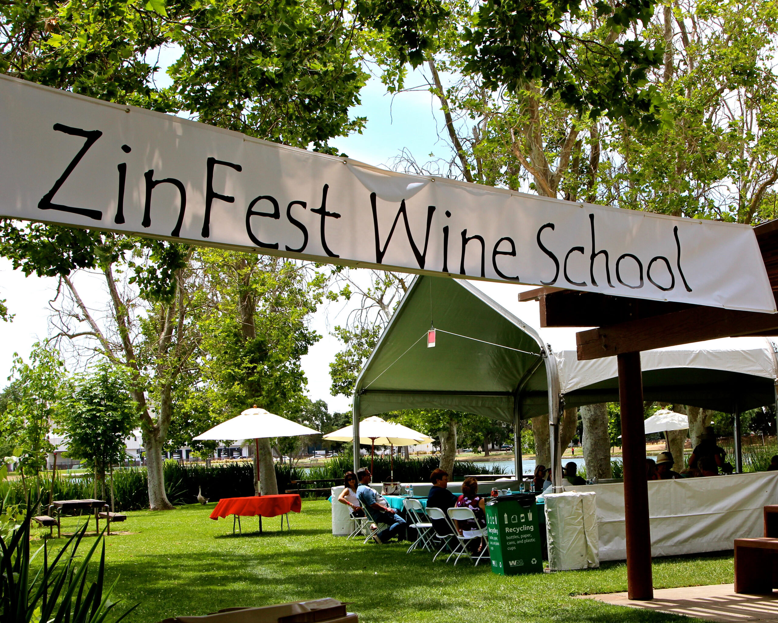 Zinfest Wine School banner at outdoor event with tents and trees in Lodi, California.