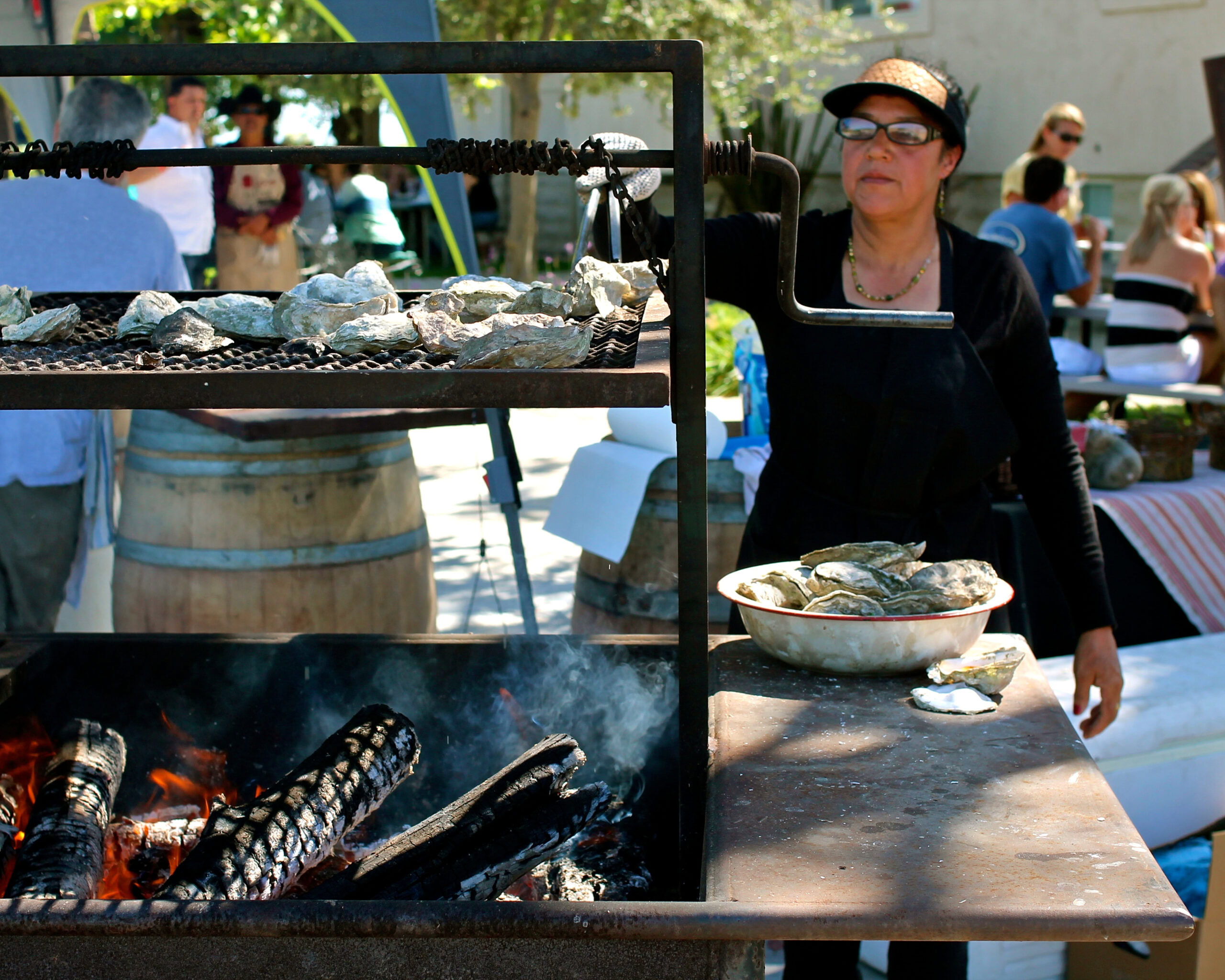 Woman grilling oysters at Lodi Winegrape Commission outdoor event in California.