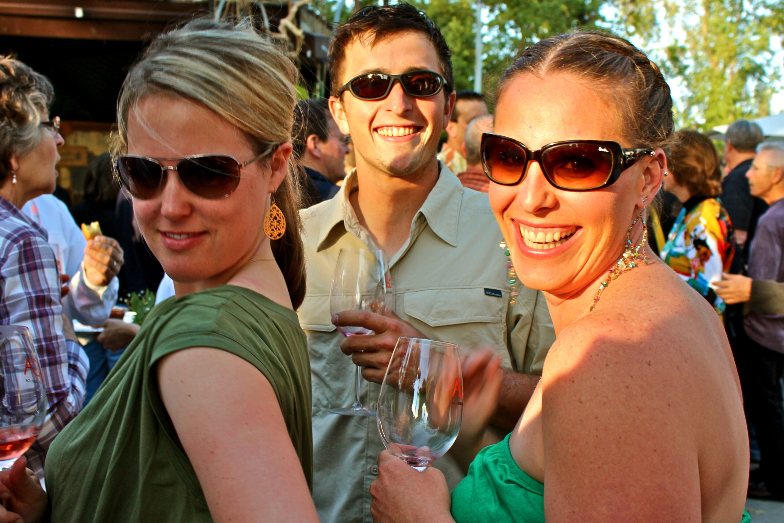 People enjoying wine at a Lodi Winegrape Commission outdoor event in sunny weather.