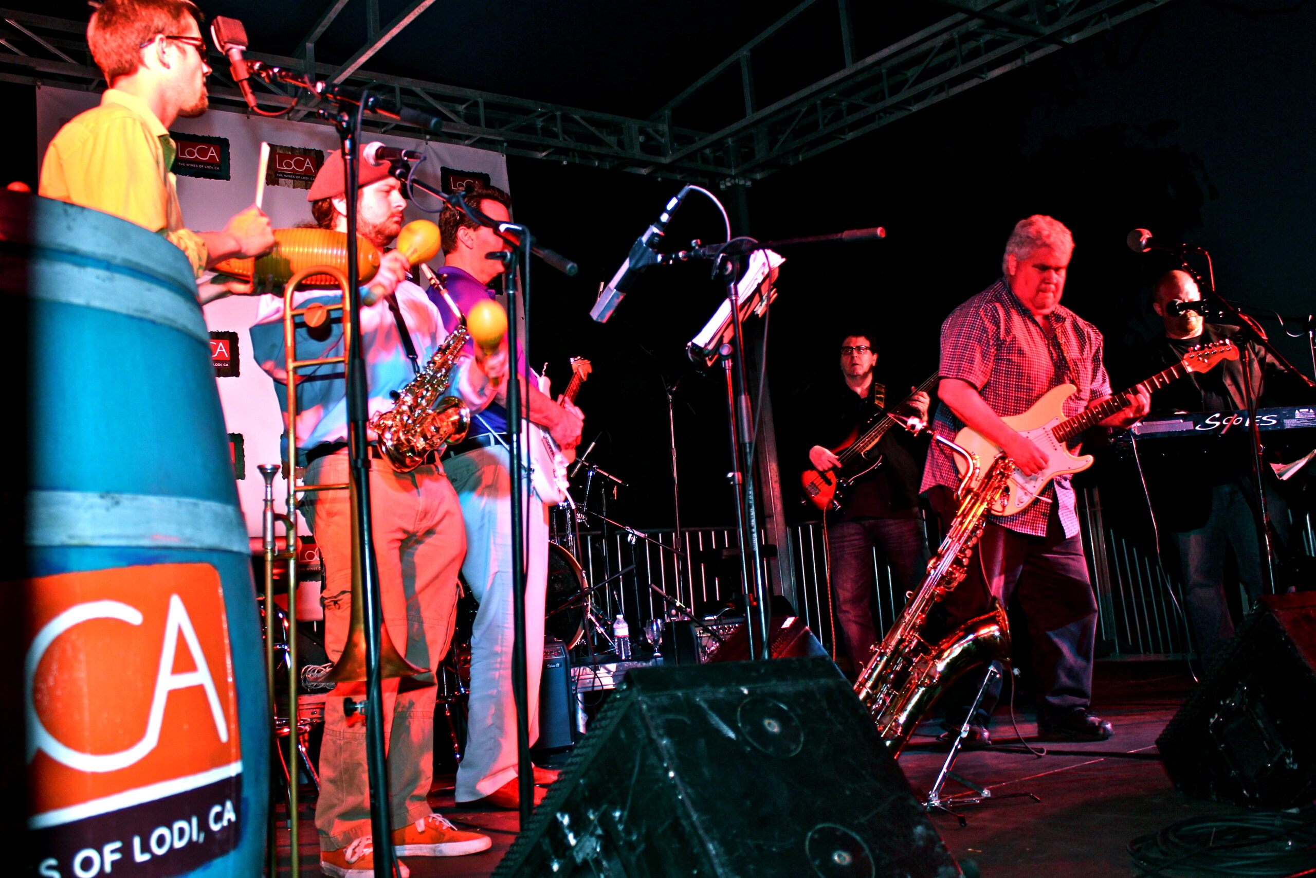 Musicians performing live on stage at a Lodi wine event, featuring a saxophonist and other band members with wine barrels in.
