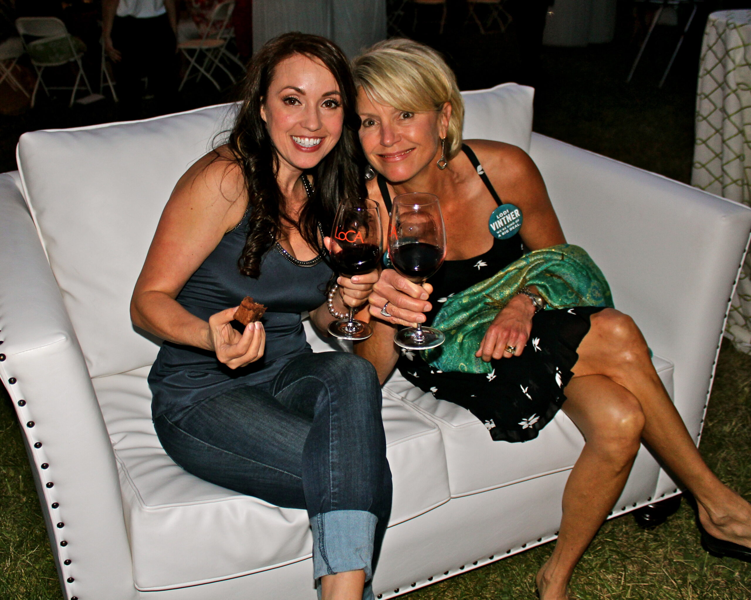 Two women enjoying wine at a Lodi Winegrape Commission event, smiling and holding glasses of red wine.