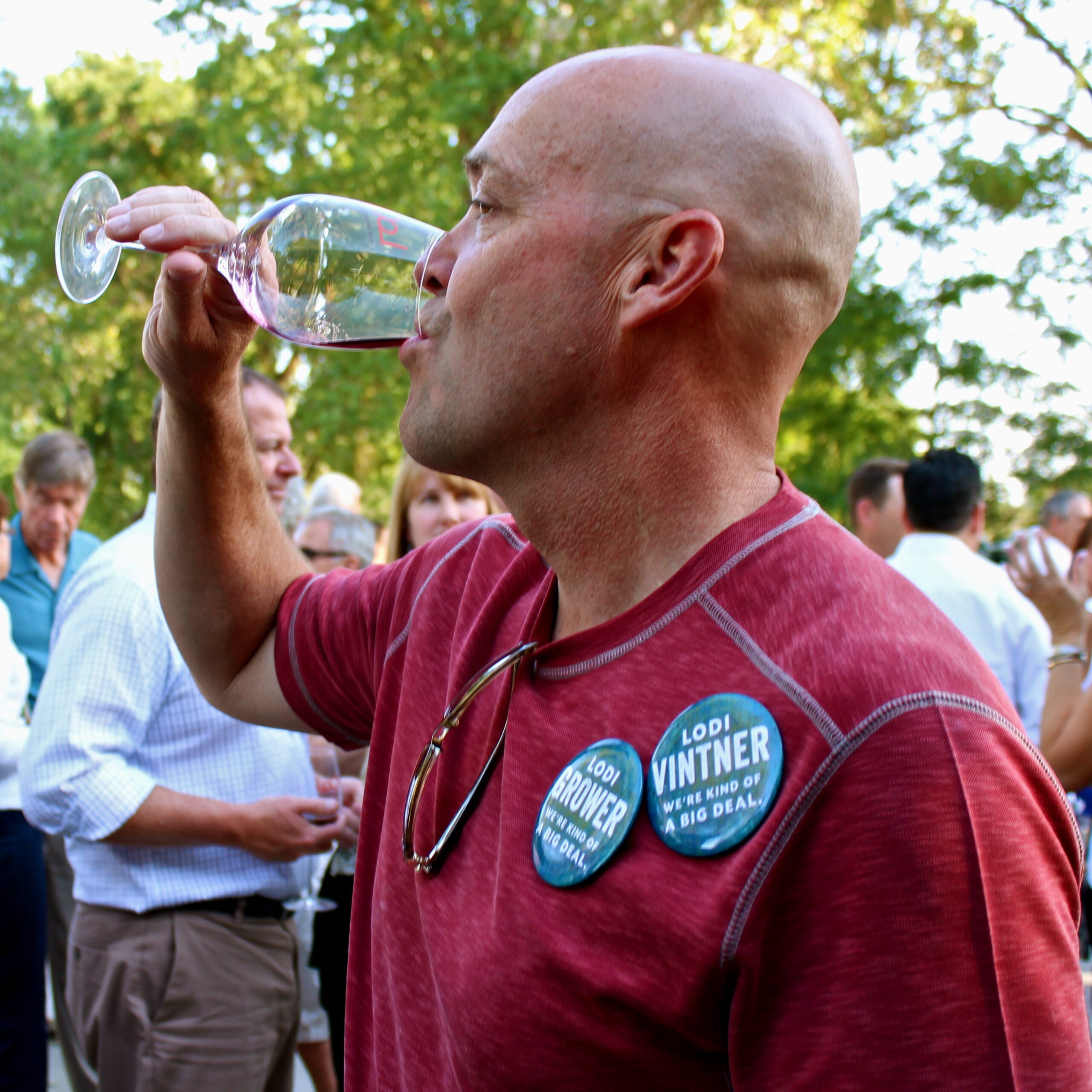 Man tasting wine at Lodi Winegrape Commission event with others in the background.