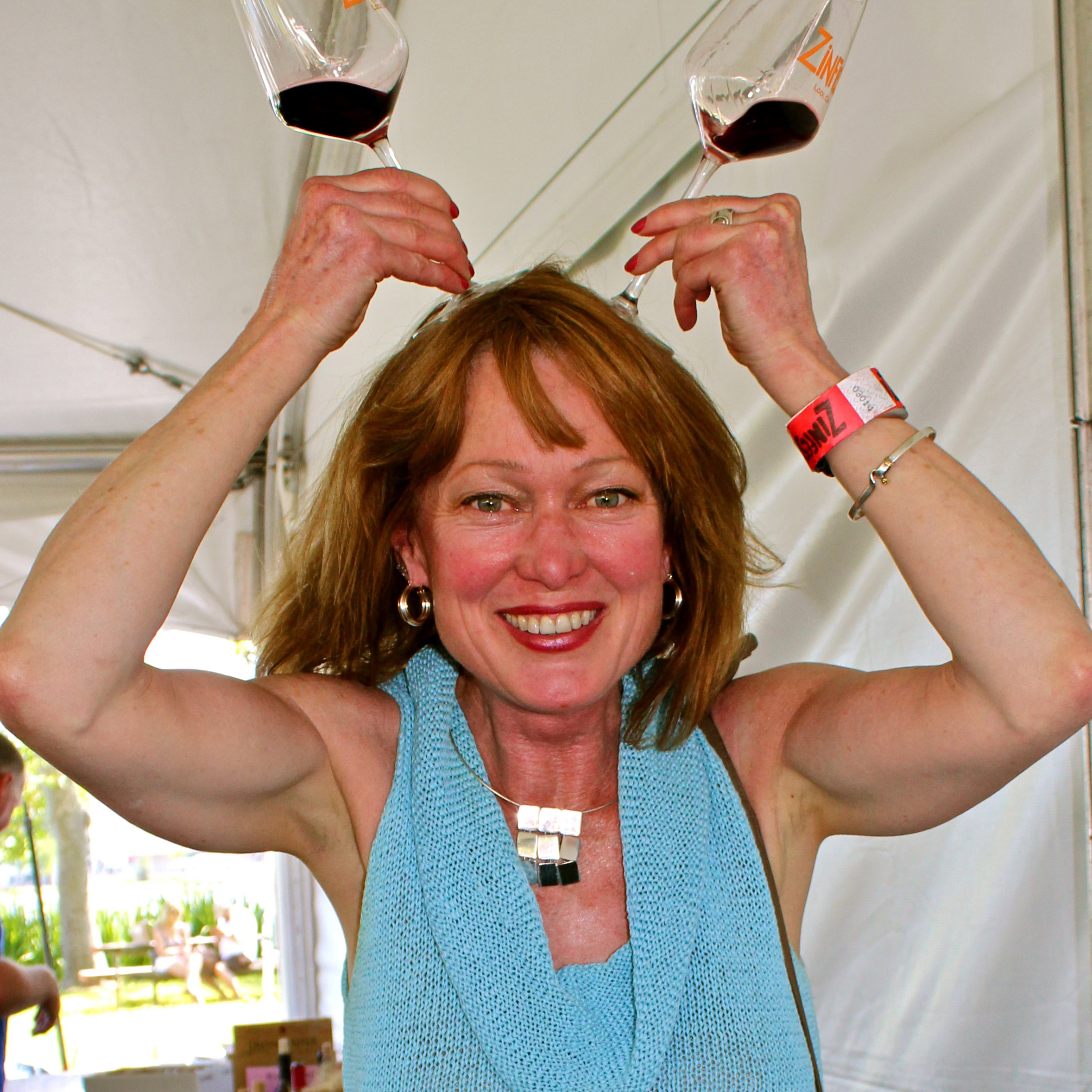 Woman celebrating with two glasses of red wine at a Lodi wine event.