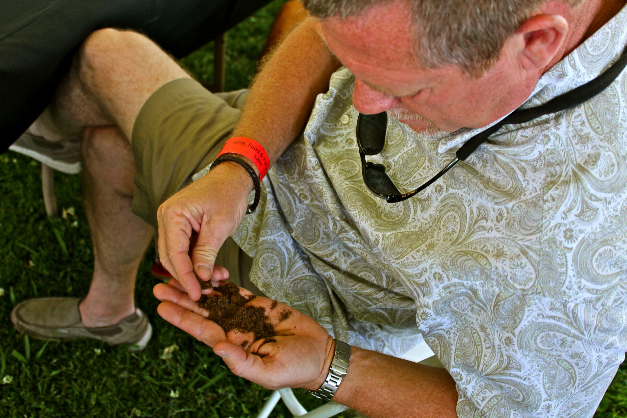 Man examining soil and grapevine soil sample at Lodi wine event for winegrape research.