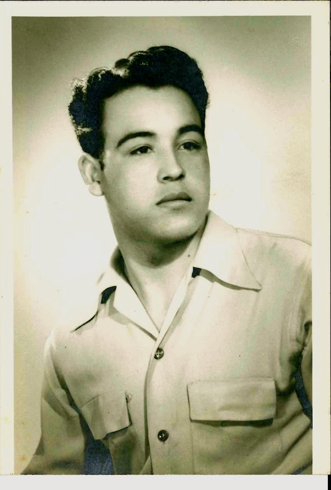Black and white vintage portrait of a young man with styled hair and a collared shirt, looking to the side.