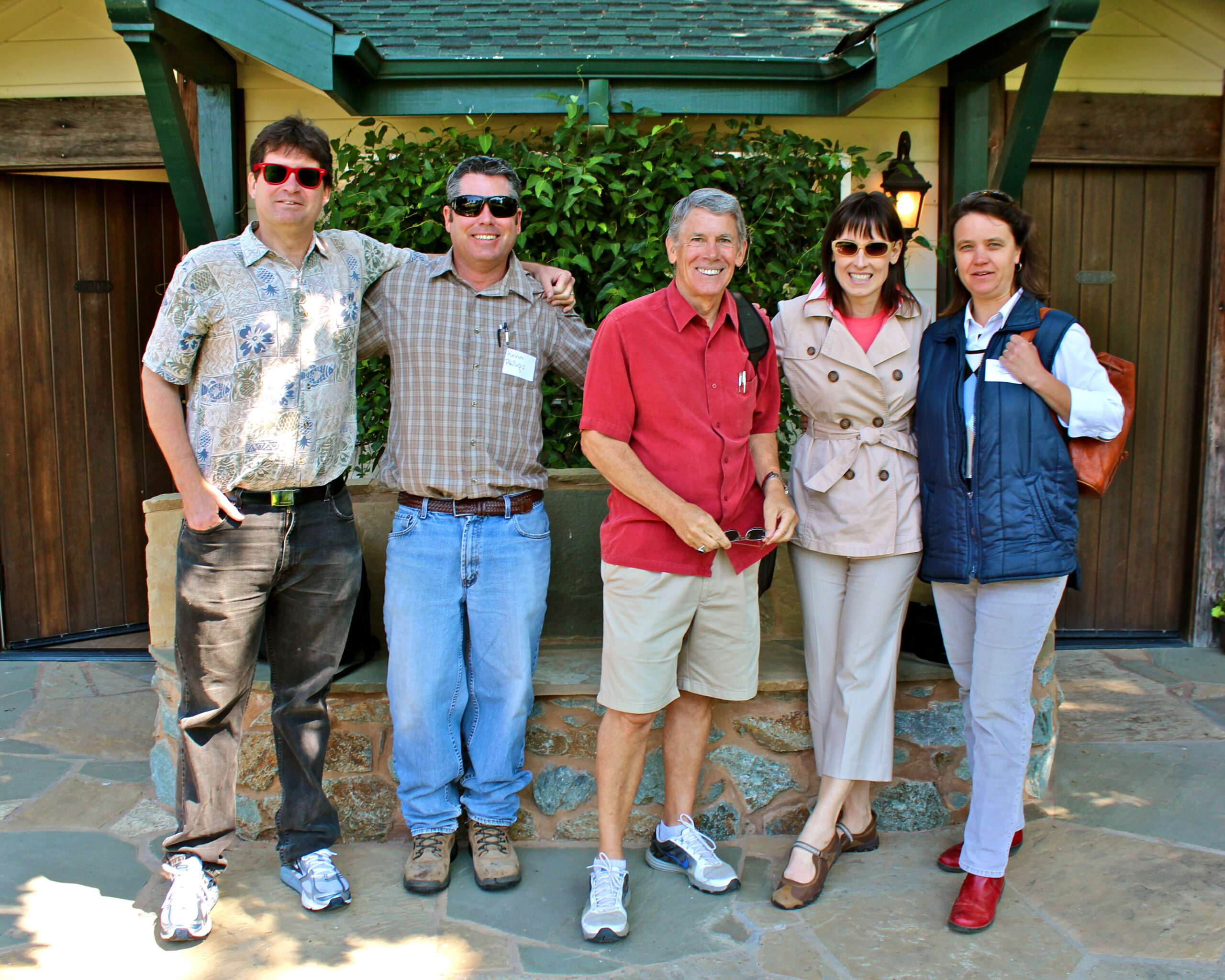 Group of five diverse adults smiling outdoors at Lodi Wine event, enjoying wine tasting and socializing.