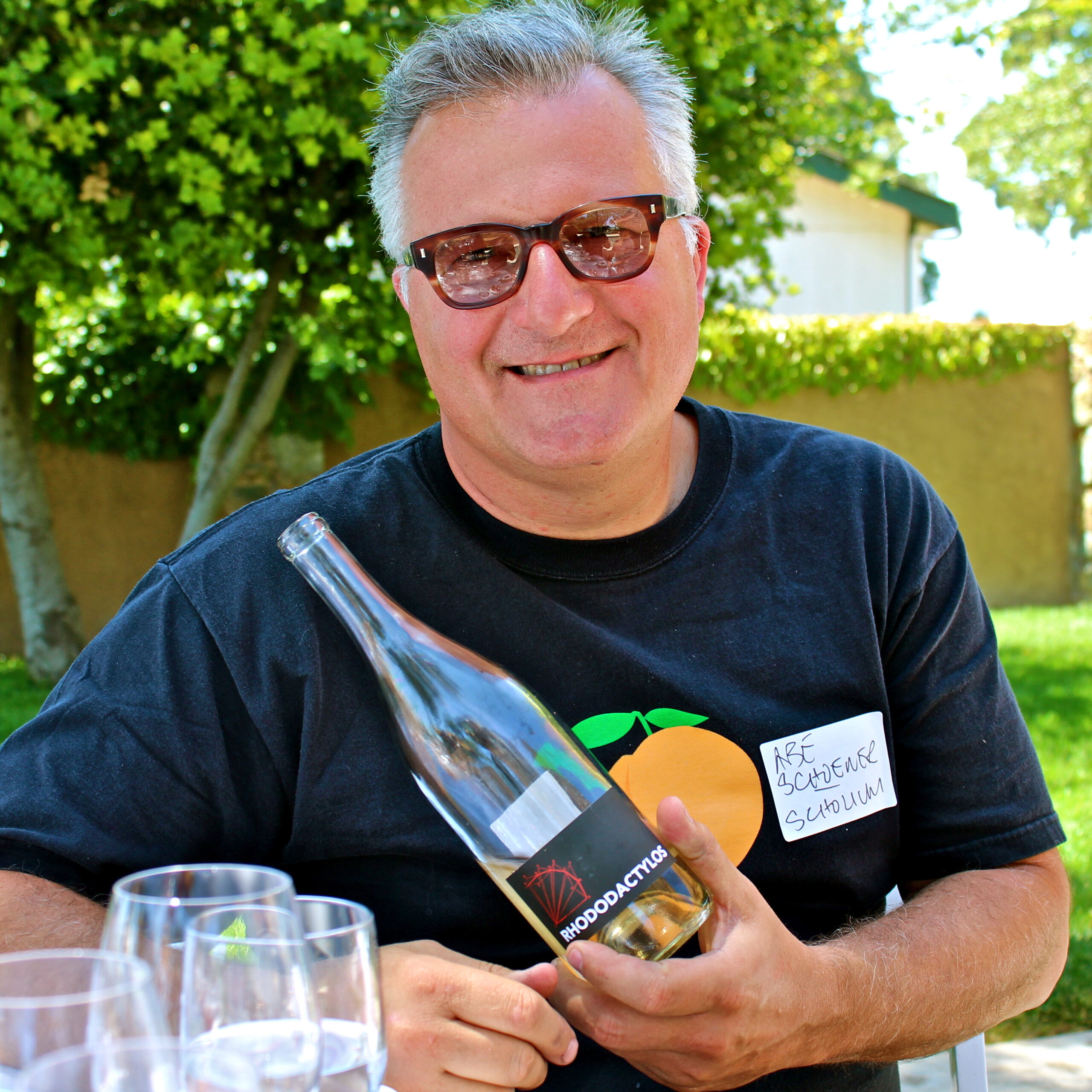 Smiling man holding a wine bottle at a Lodi wine event outdoors.