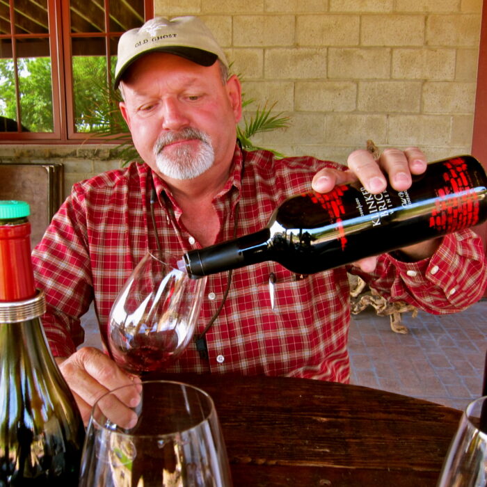 Man pouring red wine into a glass at a wine tasting event, representing Lodi Winegrape Commission.