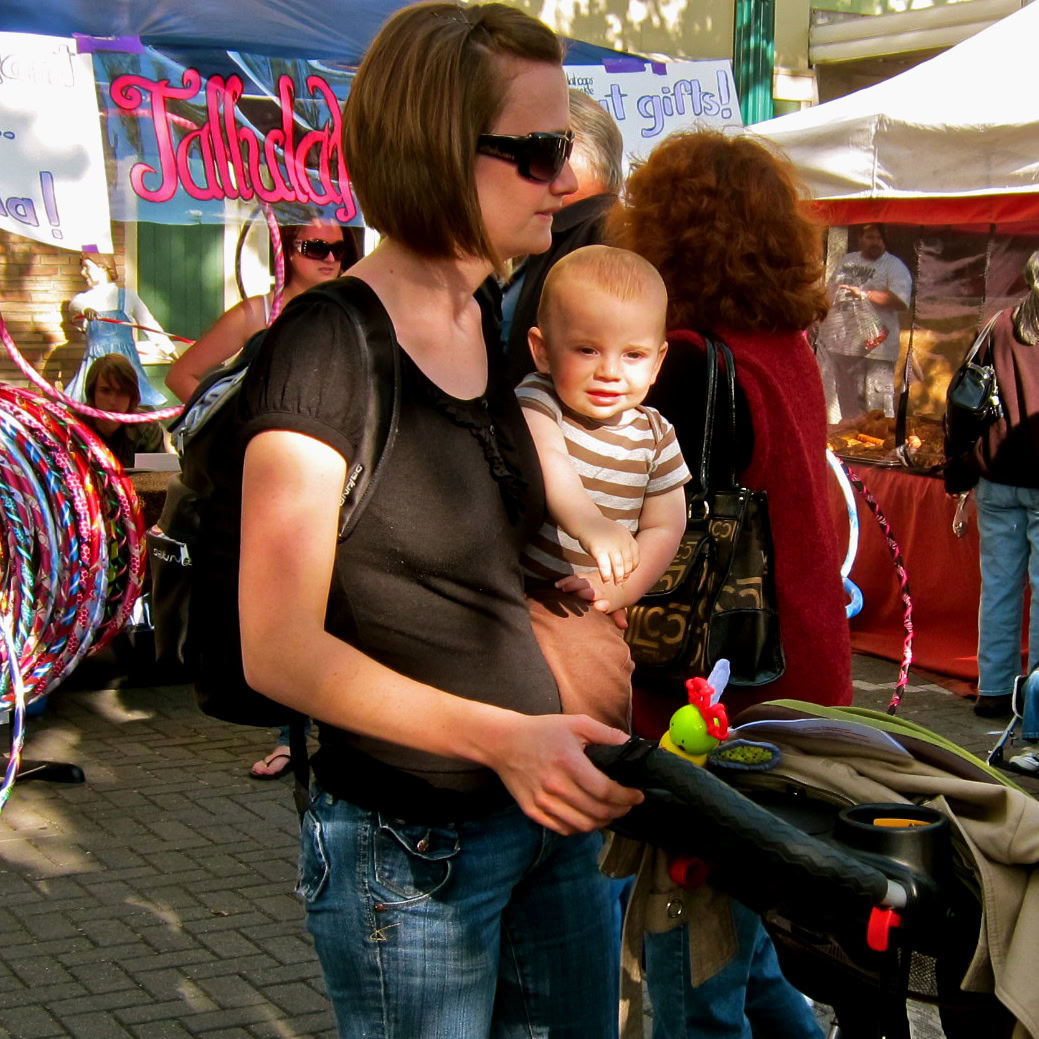 Woman with a baby at a Lodi Winegrape Commission event, outdoor market scene.