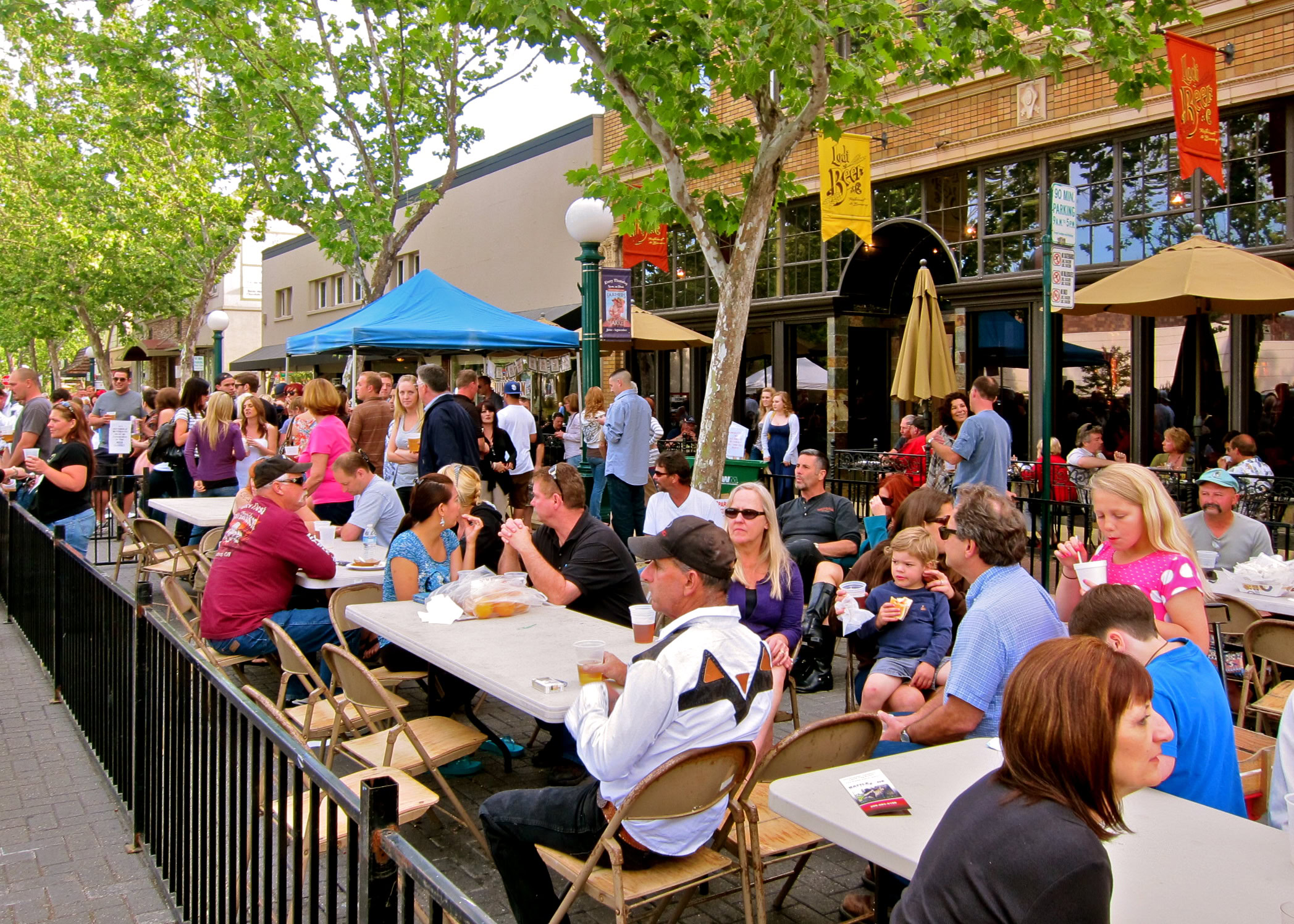 Crowd enjoying outdoor dining and wine tasting at Lodi Winegrape Festival in downtown Lodi, California.