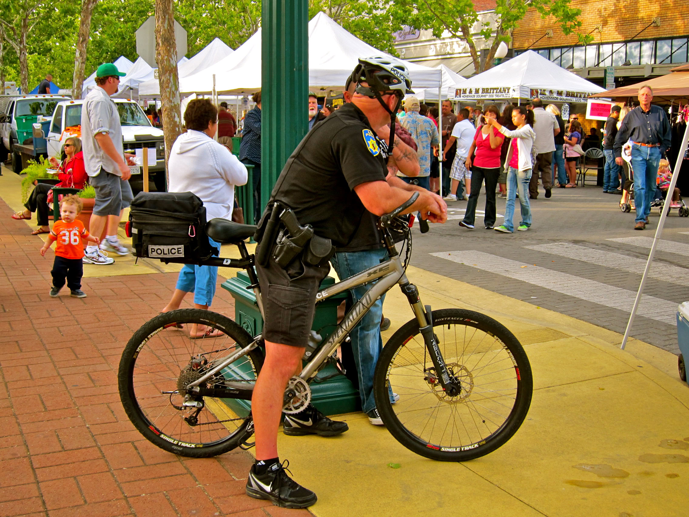 Police officer with bicycle at outdoor community event in Lodi, California.