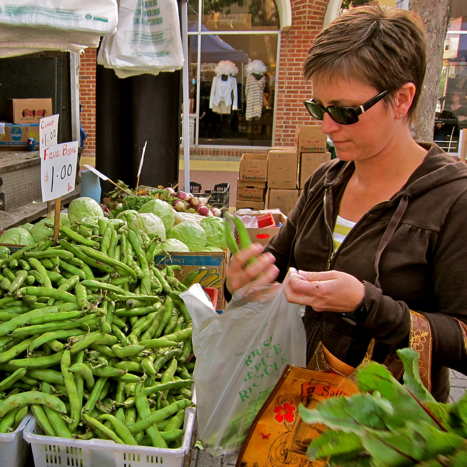 Woman shopping for fresh green vegetables at a farmers market in Lodi, California.