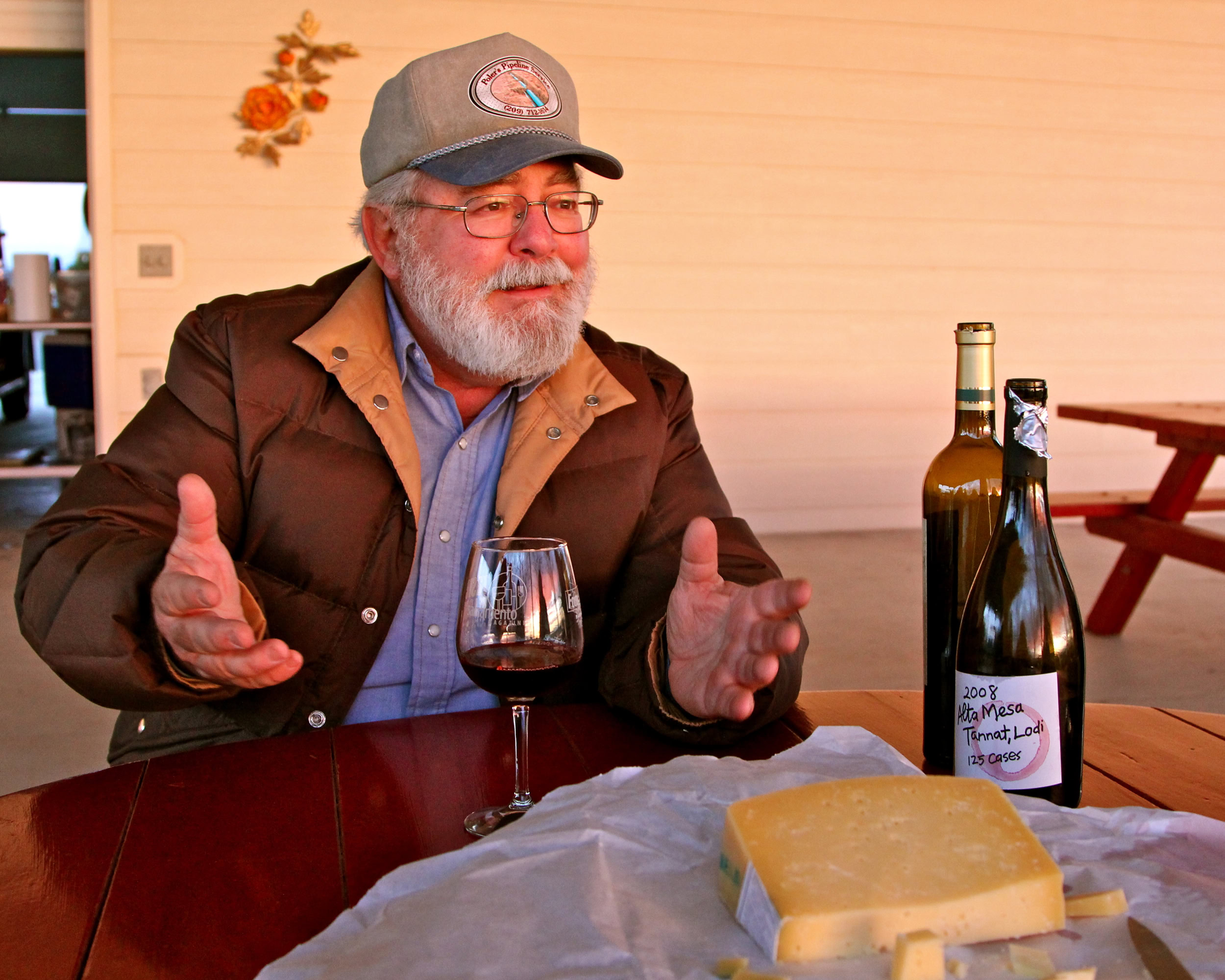 Elderly man with glasses and beard enjoying wine tasting at Lodi Winegrape Commission event.